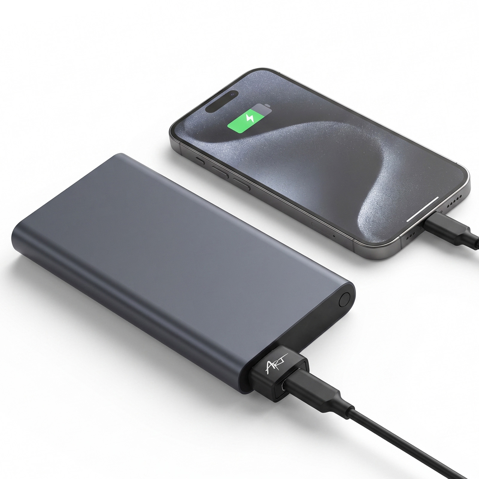 Eine graue Powerbank ist auf einer weissen Oberflaeche mit einem ladenden Smartphone verbunden.