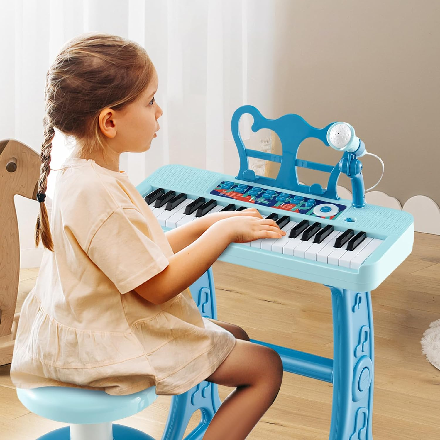 Ein junges Mädchen in einem beigen Kleid spielt auf einem hellblauen Kinderkeyboard mit Mikrofon.