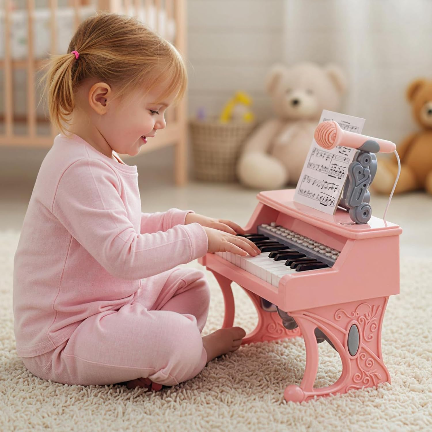 Kleines Mädchen in rosa Kleidung sitzt auf einem Teppich und spielt auf einem kleinen rosa Spielzeugklavier.