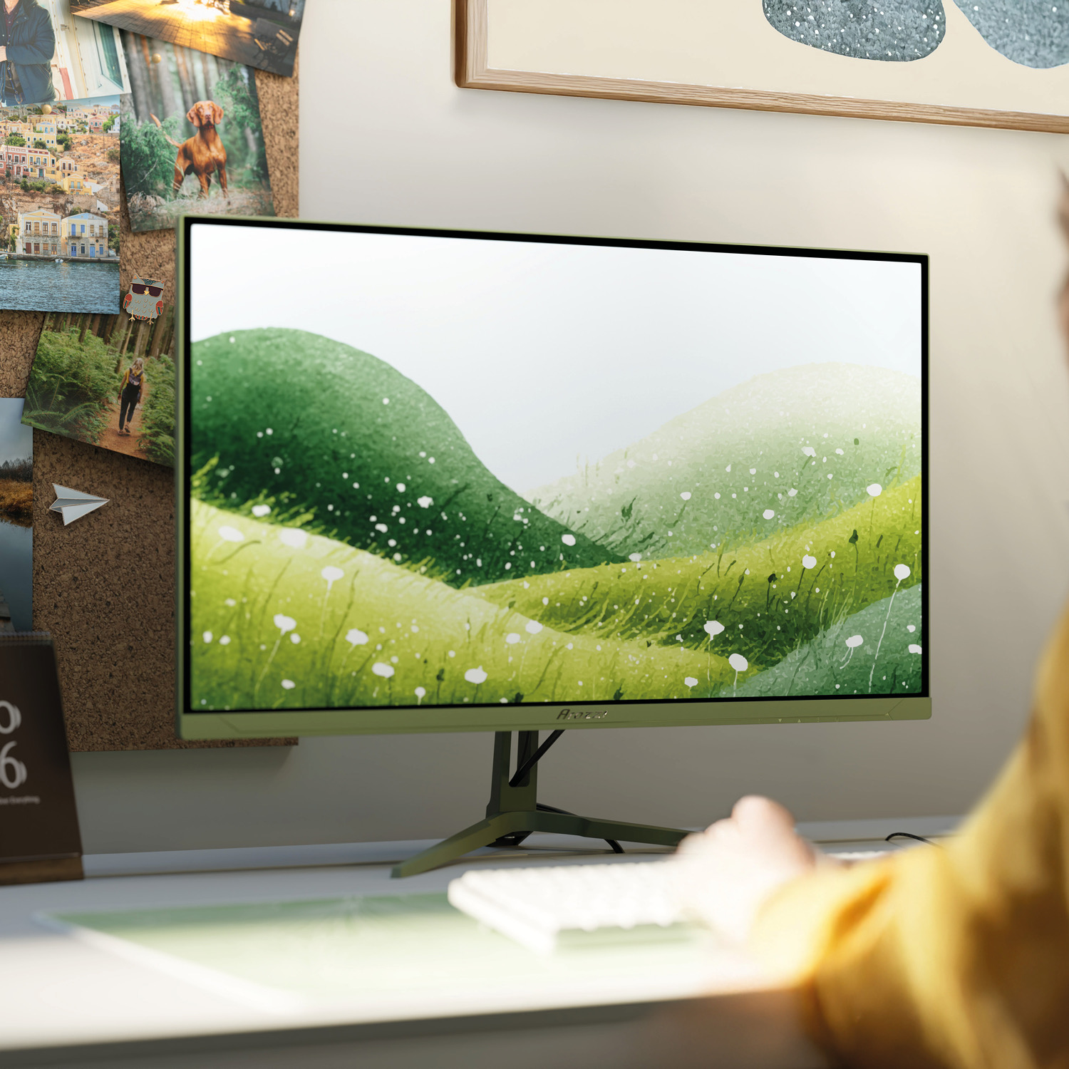 Ein grüner Monitor mit einer bergigen Landschaft als Hintergrundbild steht auf einem Schreibtisch.