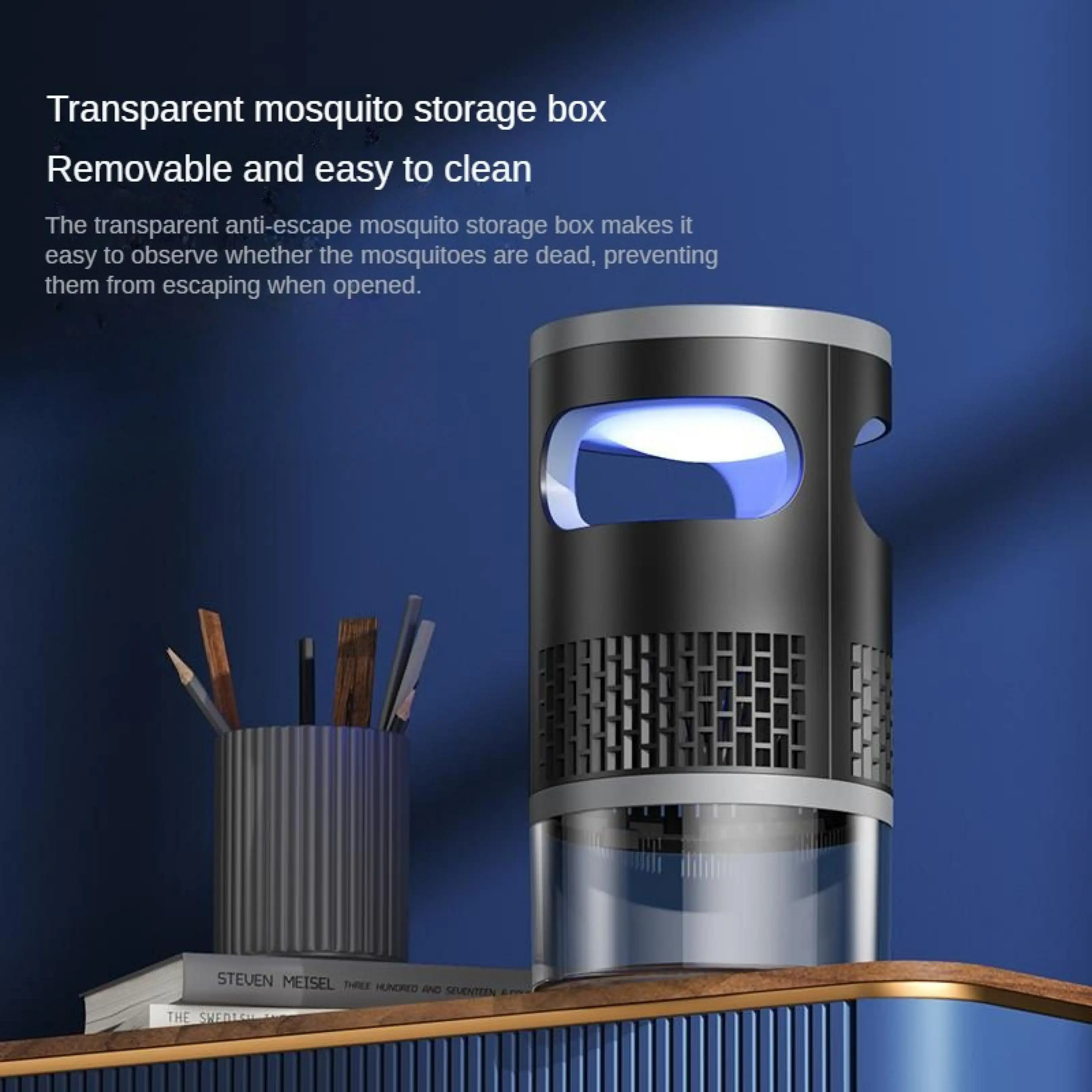 Ein schwarzer elektronischer Mückenvernichter mit blauem Licht steht auf einem Tisch neben Stiften und Büchern.