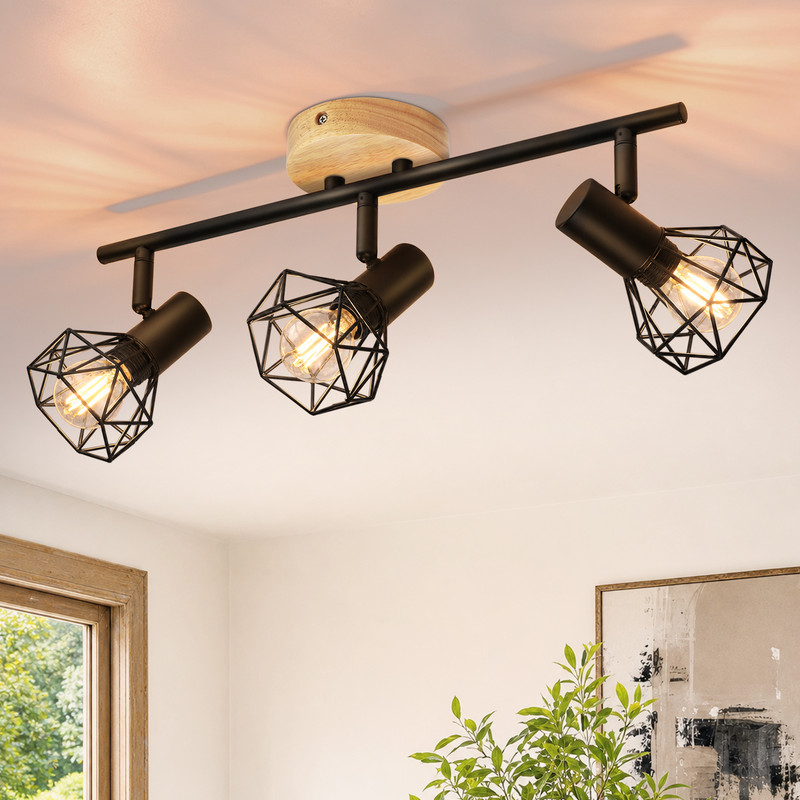 Moderne Deckenleuchte mit drei schwarzen Metallkäfig-Strahlern und Holzelement an weißer Decke.