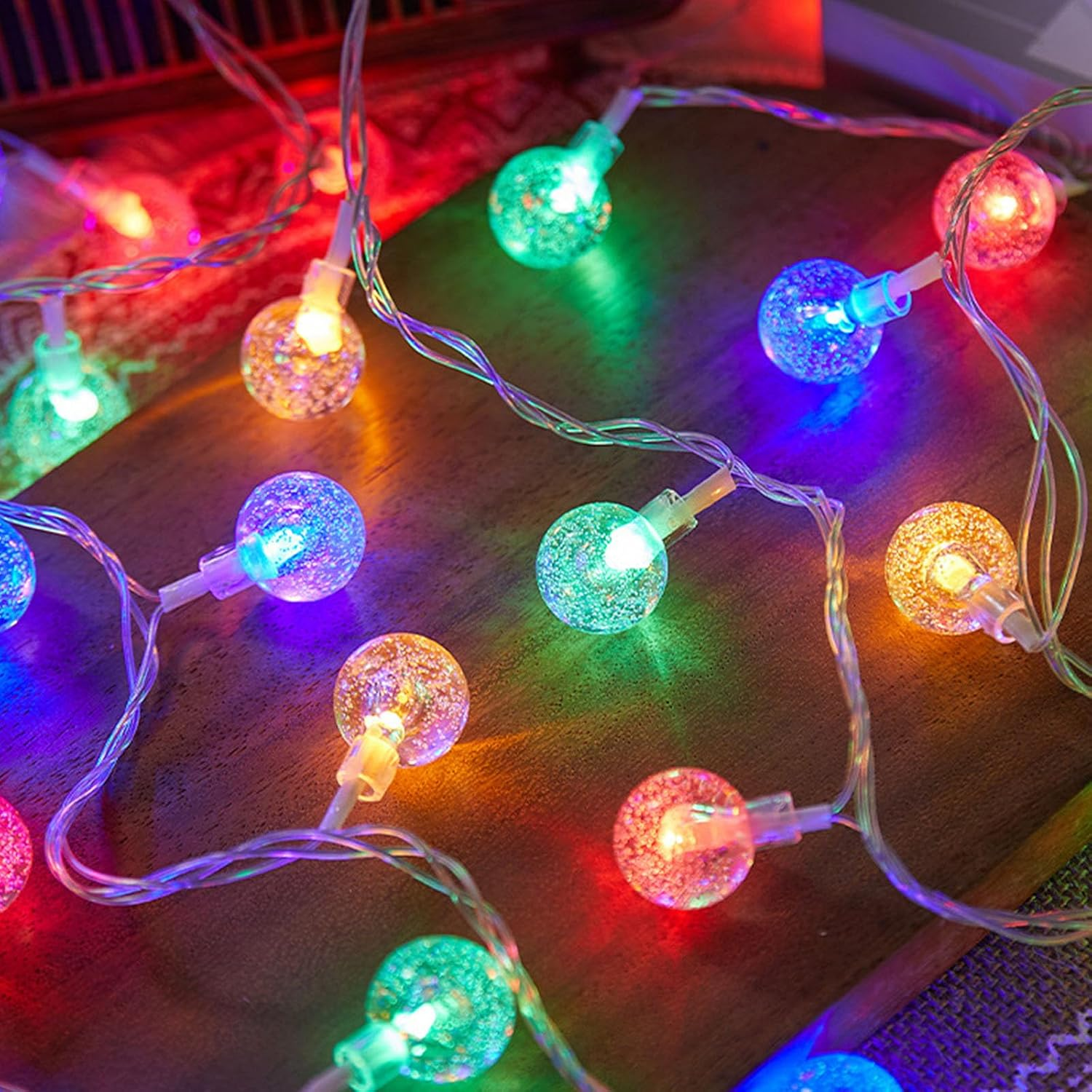 Bunte, leuchtende Kugel-Lichterkette auf einer Holzoberfläche.