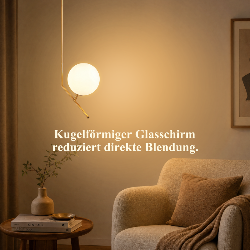 Eine Leuchte mit Glasball hängt über einem gemütlichen Sessel mit Kissen neben einem Holztisch mit Vase.