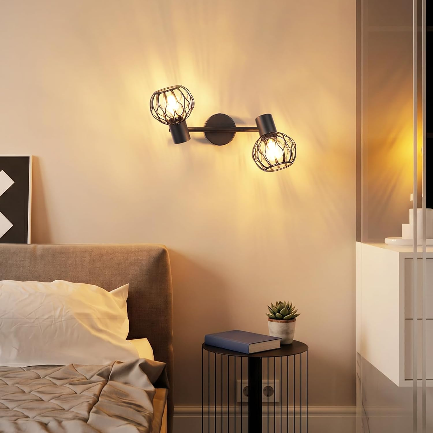 Wandleuchte mit zwei Käfig-Spots über einem Bett, daneben ein Nachttisch mit Buch und Pflanze.