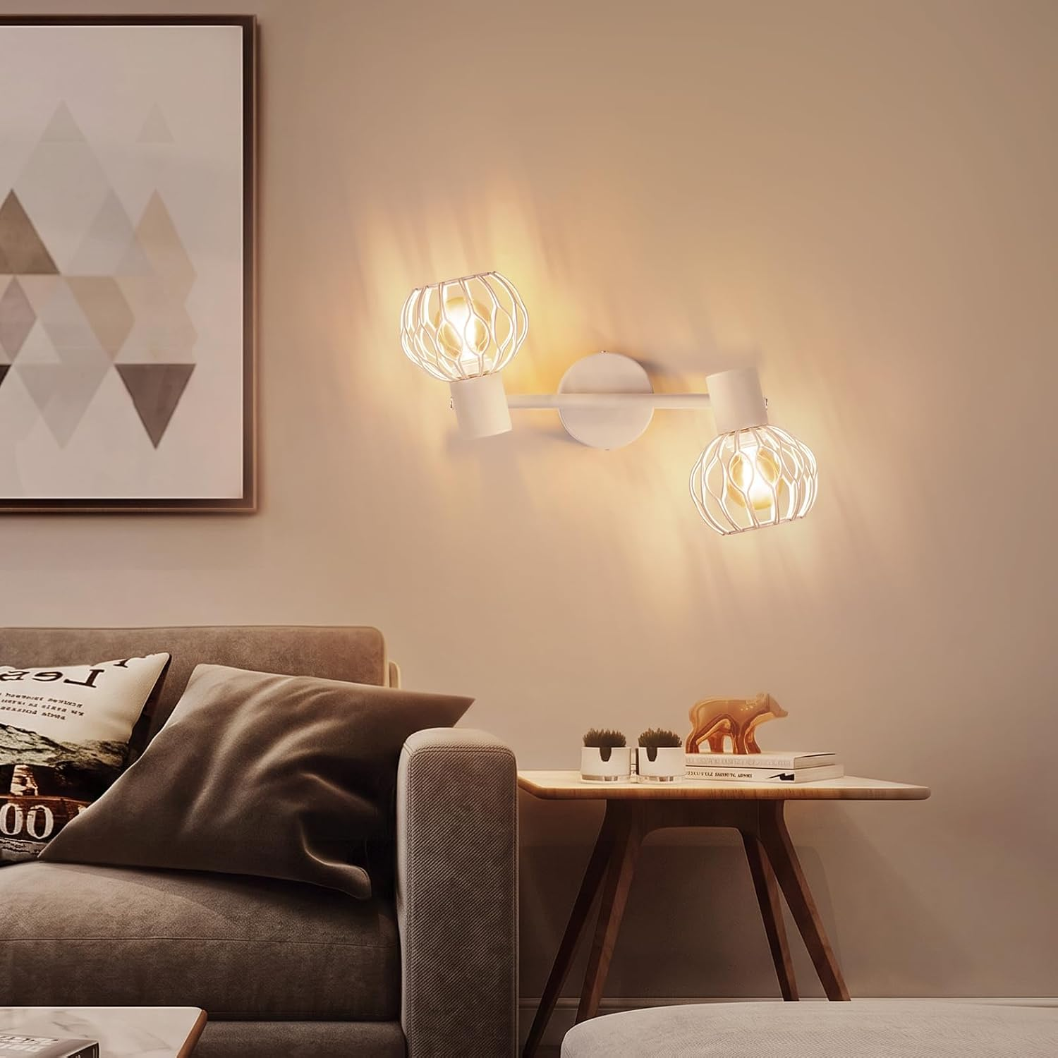 Eine moderne weiße Wandlampe mit zwei runden Drahtschirmen leuchtet über einem Sofa und Beistelltisch.