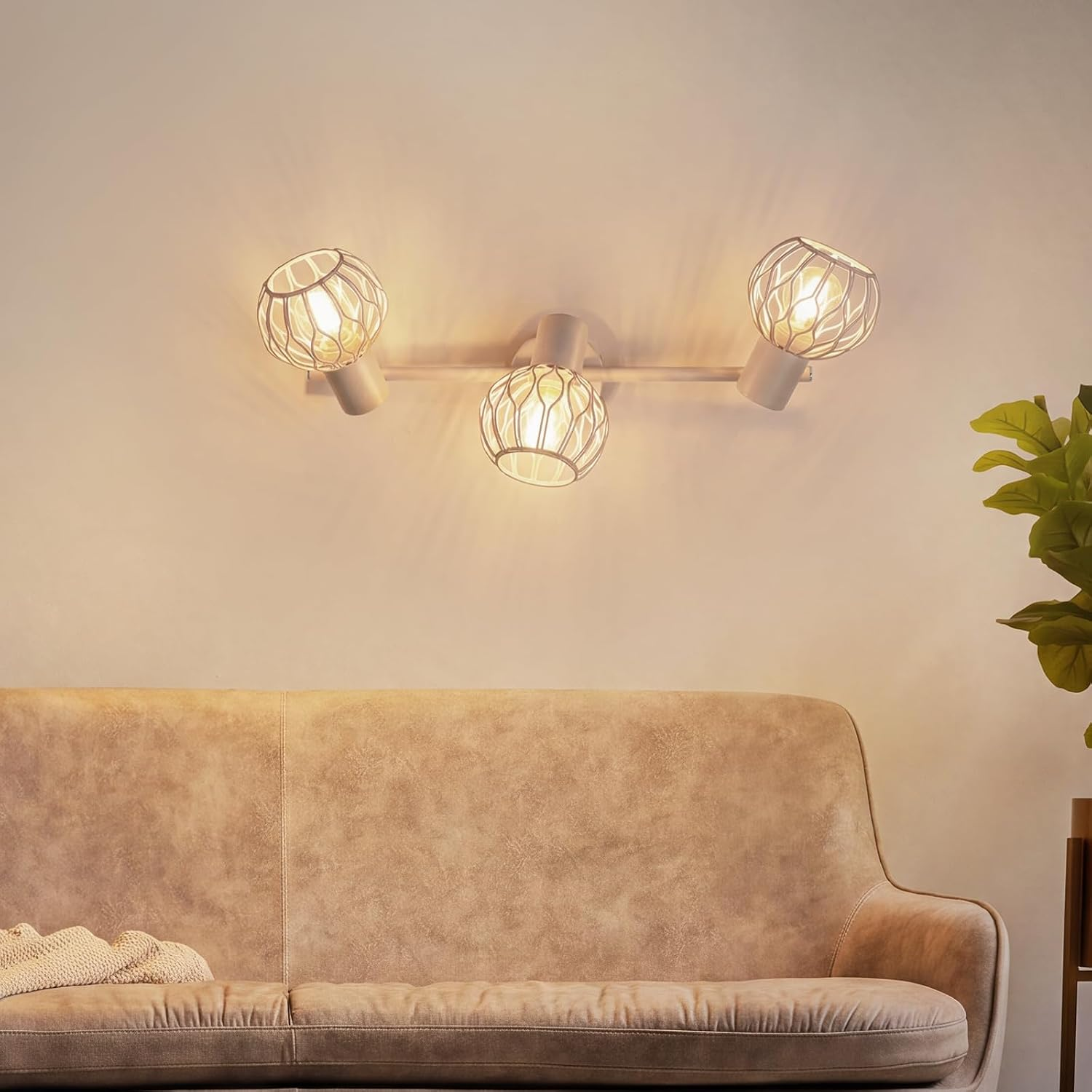 Wandlampe mit drei Schirmen über einem hellbraunen Sofa in einem ruhigen Zimmer.