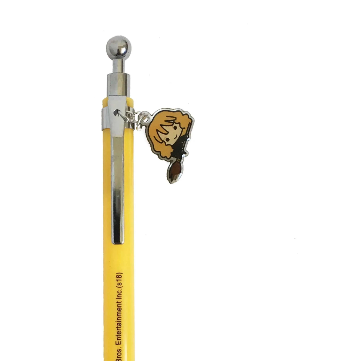 Ein gelber Stift mit silbernem Clip und einer kleinen Anhängerfigur, die eine Hexe auf einem Besen darstellt.