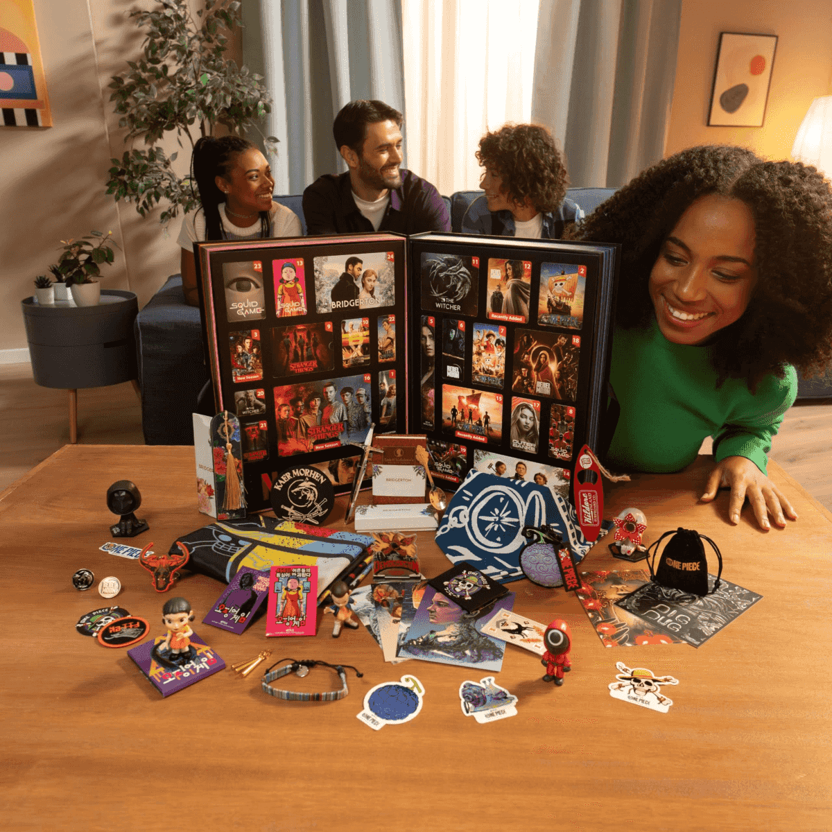 Vier Freunde lächeln an einem Holztisch mit Fanartikeln und einem offenen Adventskalender.
