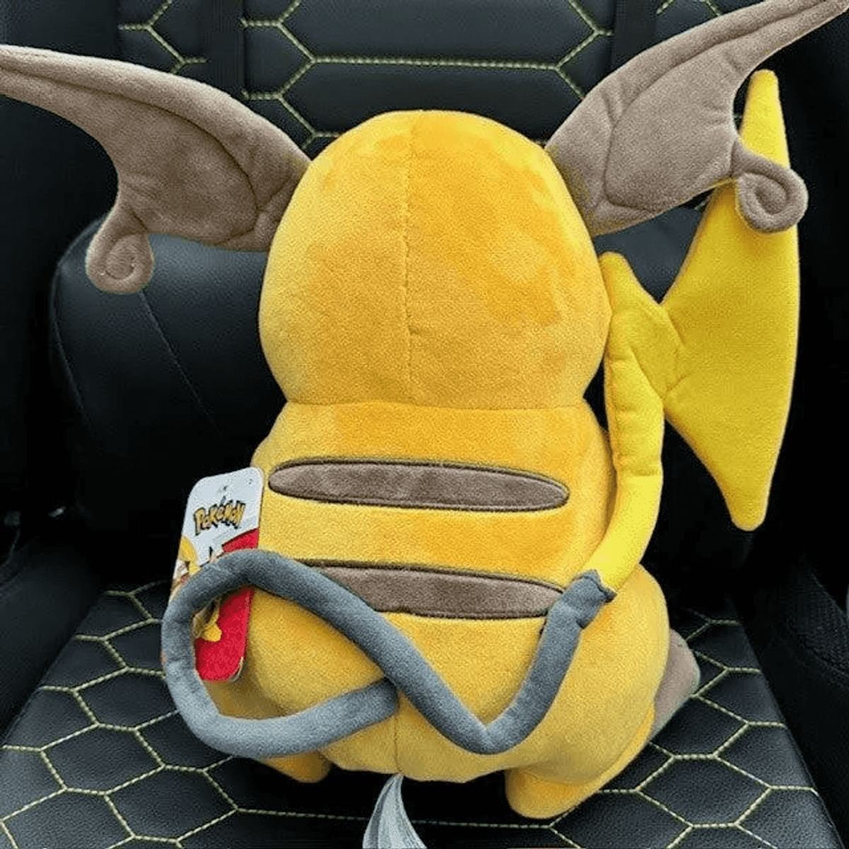 Rückansicht eines gelben Raichu-Plüschtiers mit großen braunen Ohren, einem geschwungenen Schwanz und einem Pokémon-Etikett.