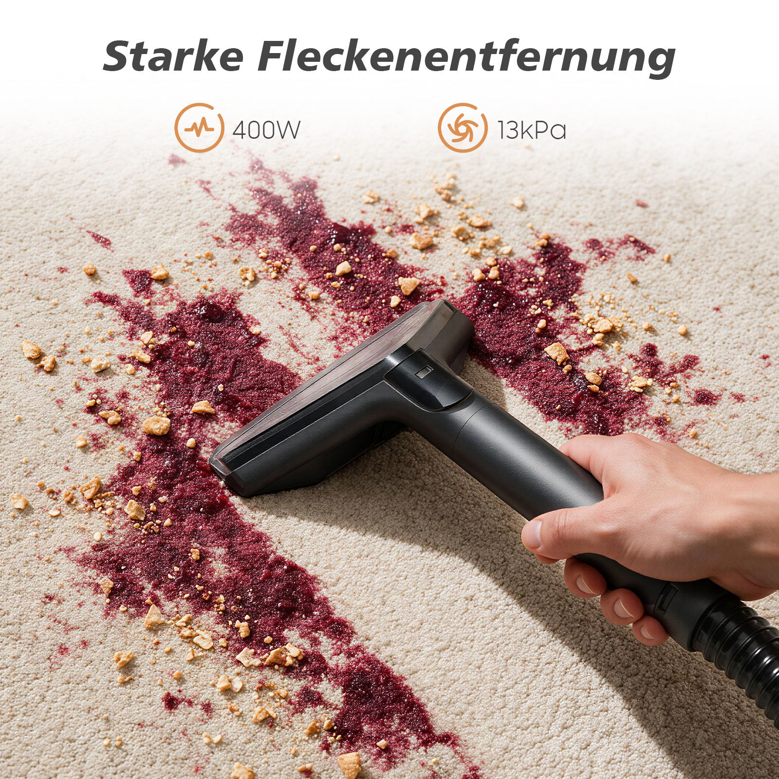 Ein Handstaubsauger reinigt roten Fleck und Krümel auf hellem Teppich.