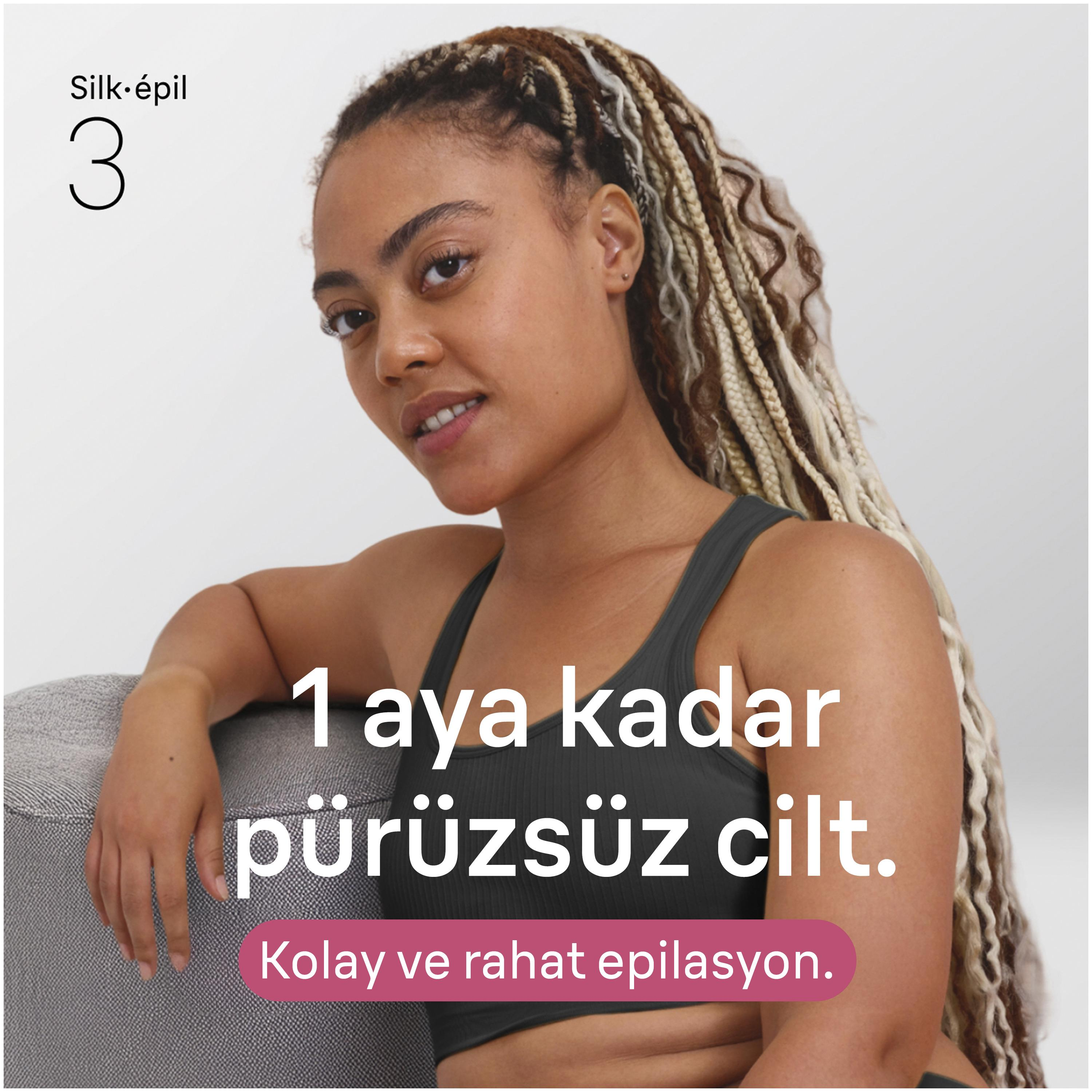 Koyu renk üst giyen, örülü sarı saçlı bir kadın gri bir koltuğa yaslanıyor.