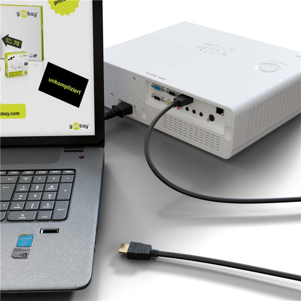 Ein grauer Laptop ist mit einem Kabel an einen weißen Beamer angeschlossen, vor einem grauen Hintergrund.