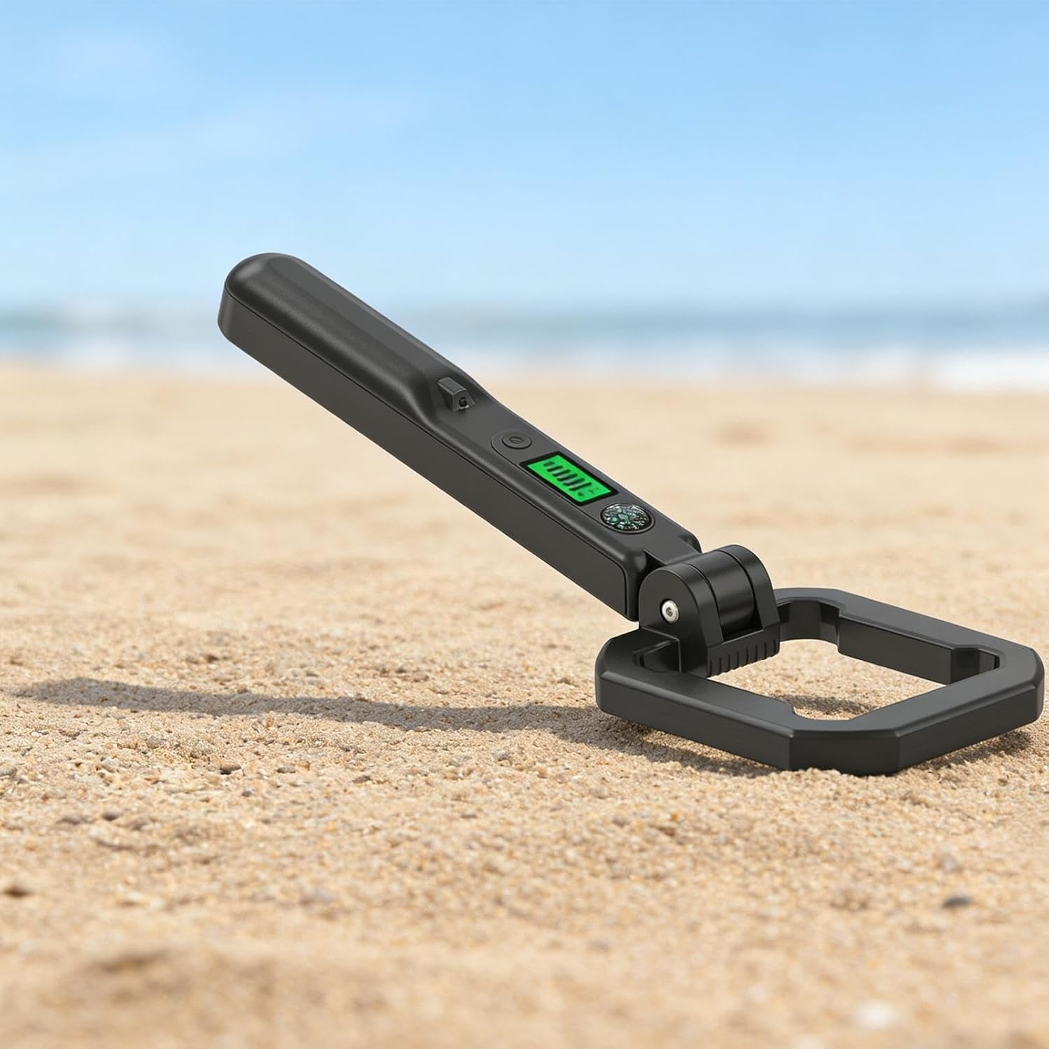 Ein schwarzer Handmetalldetektor liegt im Sand am Strand.