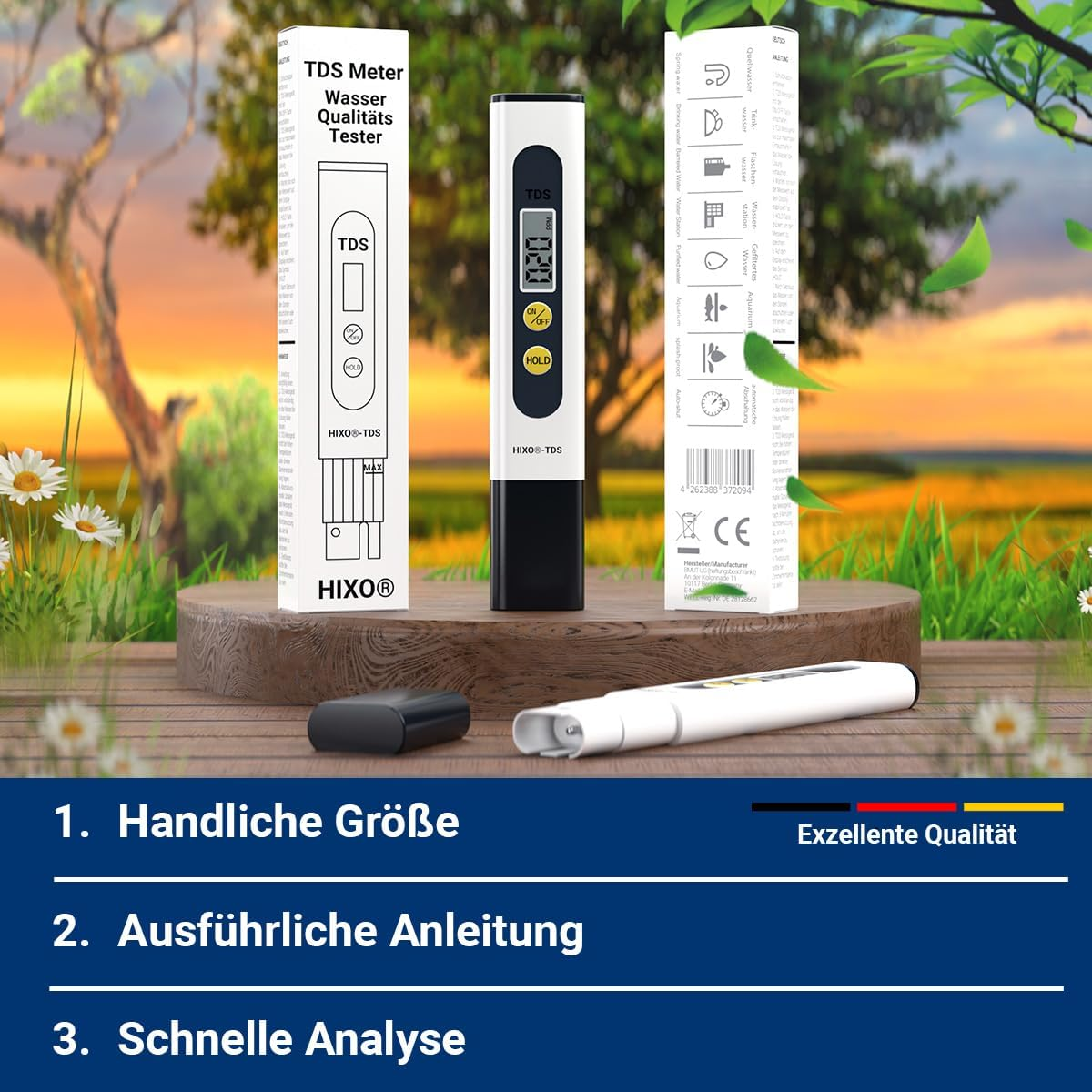 Ein weißes TDS-Messgerät mit Verpackung steht auf einem Holzständer vor einer sommerlichen Naturlandschaft.