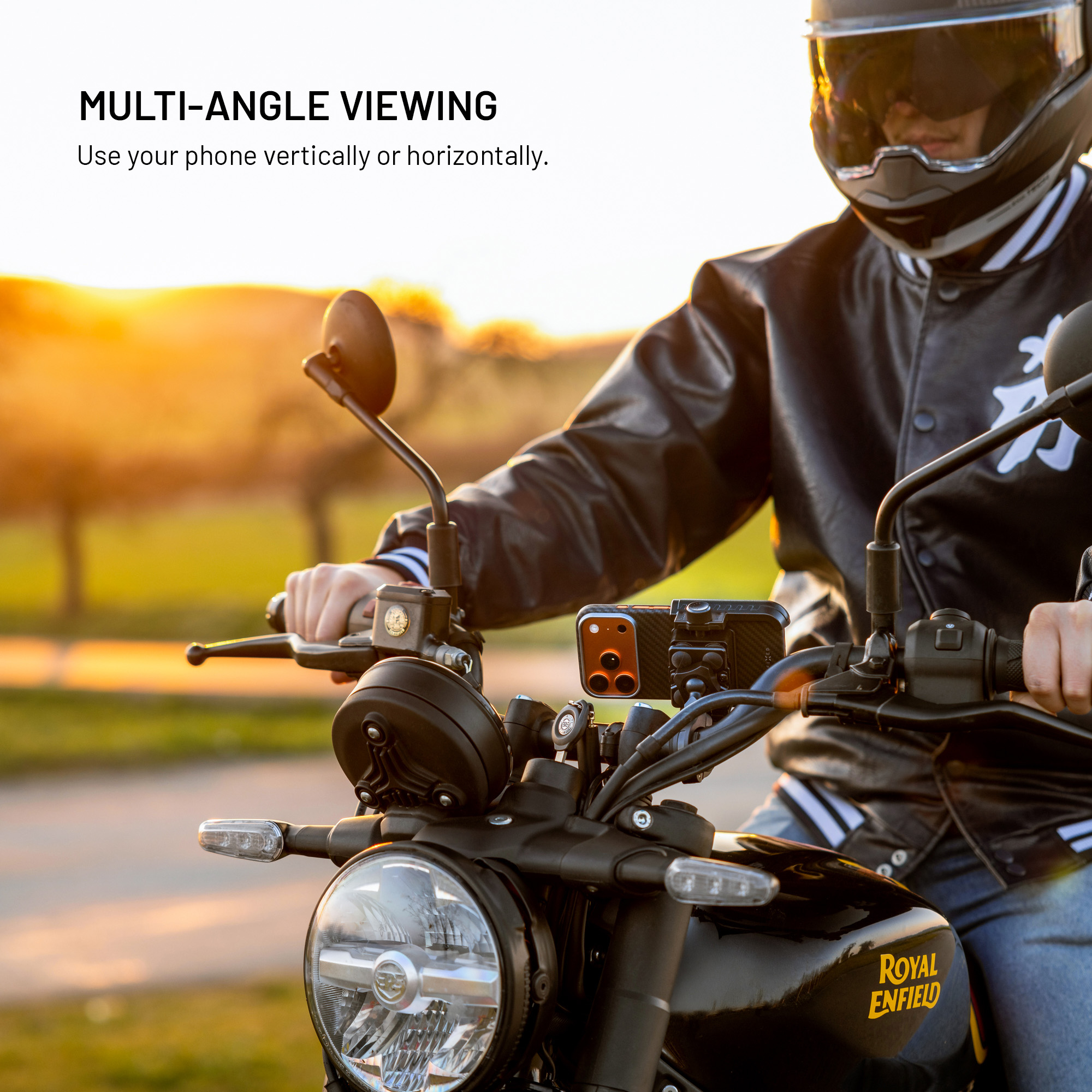 Ein Motorradfahrer mit Helm und Lederjacke fährt bei Sonnenuntergang ein Motorrad mit Handyeinlage.