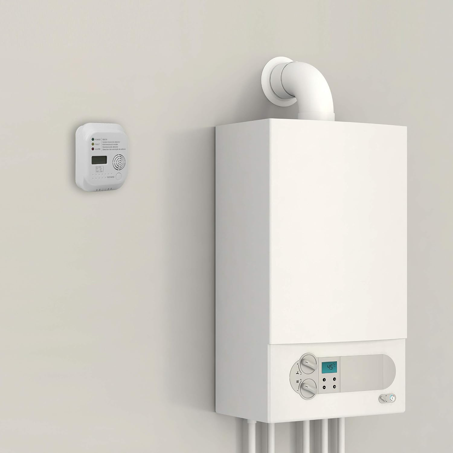 Eine weiße Gastherme an heller Wand mit Kohlenmonoxidmelder daneben und Rohren darunter.