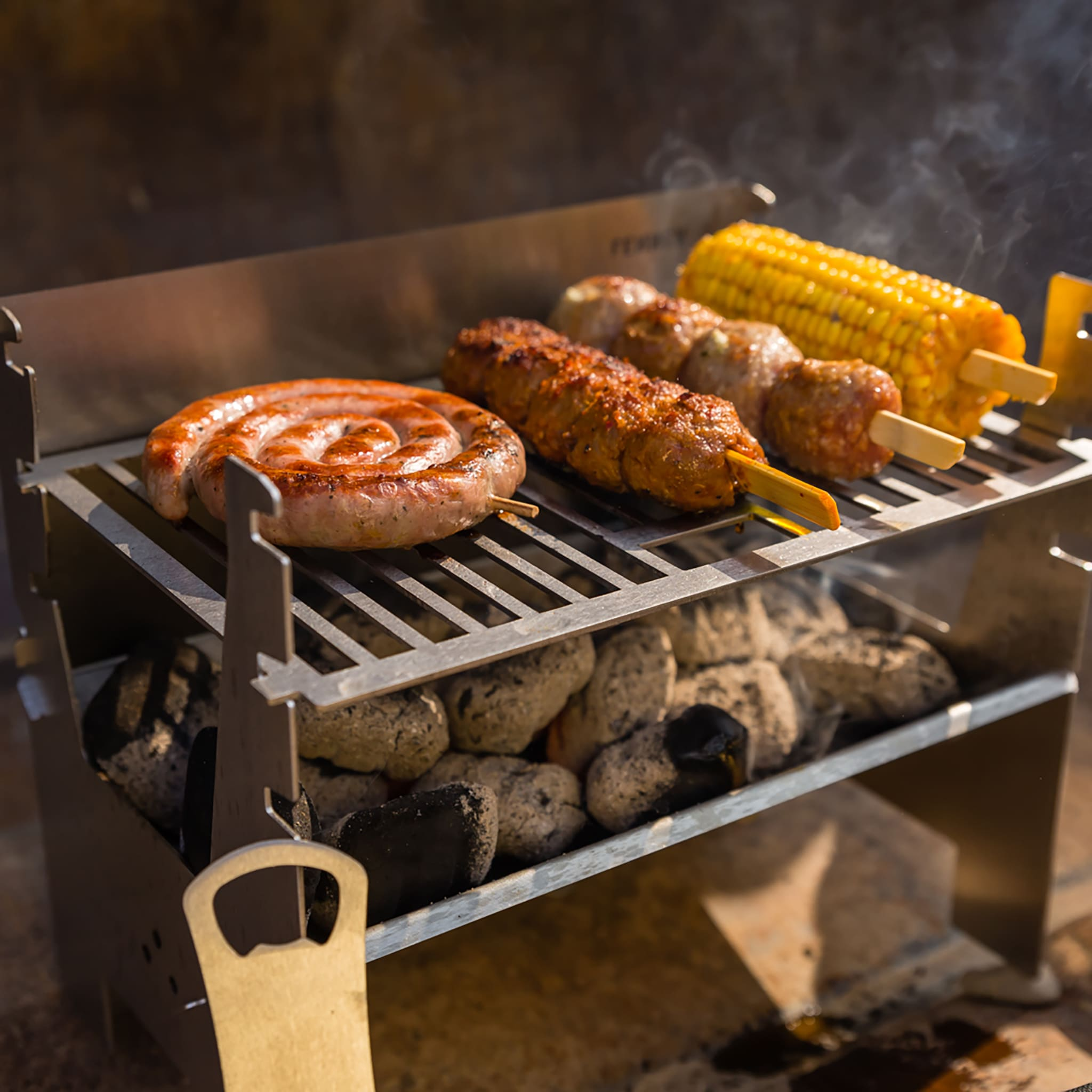 Grillwürste, Fleischspieße und Mais auf einem tragbaren Holzkohlegrill.