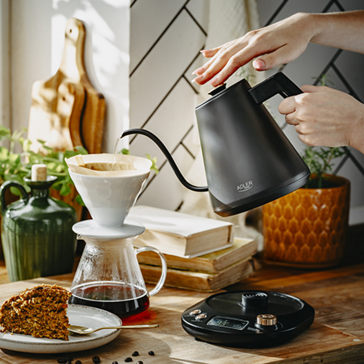 Una persona vierte agua de una tetera negra en un gotero de café en un mostrador de madera.