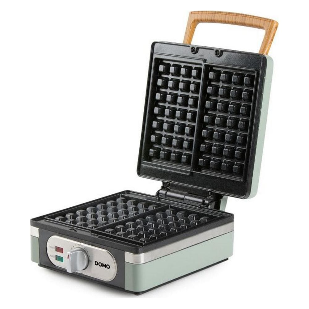 Piastra per waffle verde chiaro aperta con griglie nere antiaderenti e manico in legno.