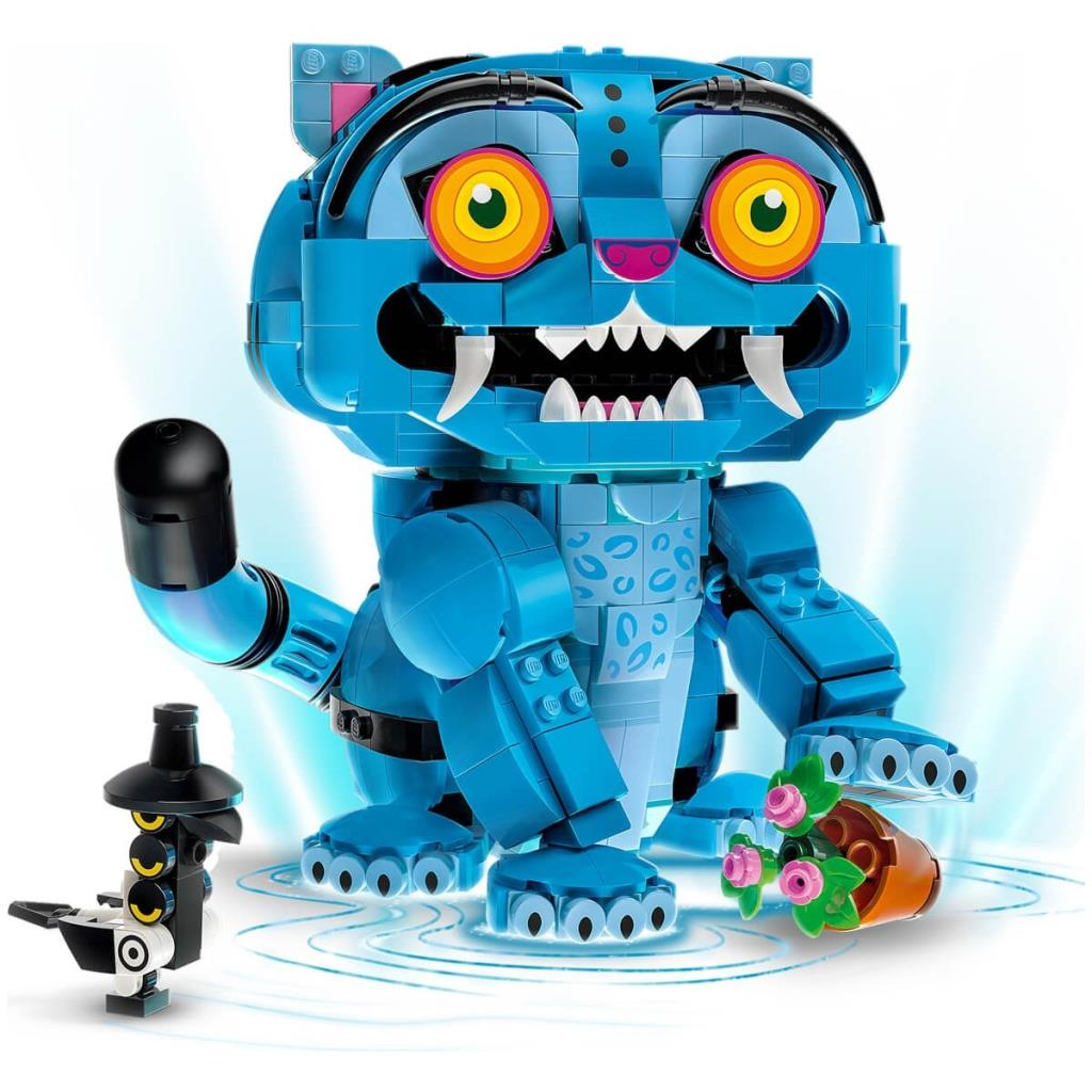 Büyük sarı gözleri ve beyaz dişleri olan mavi bir Lego kedisi küçük bir saksı bitkisi tutuyor, yanında bir kuş figürü var.