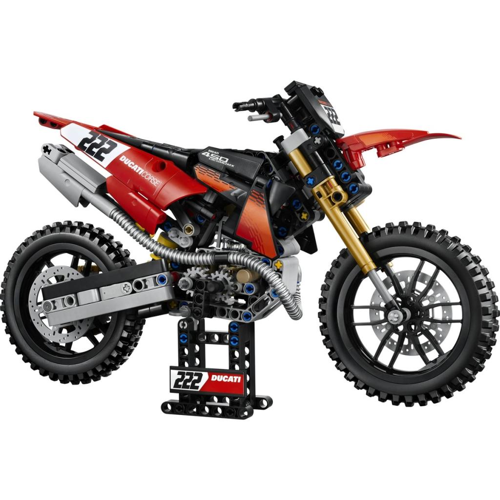 Beyaz arka plan önünde bir stant üzerinde duran kırmızı ve siyah Ducati arazi motosikletinin detaylı Lego Technic modeli.