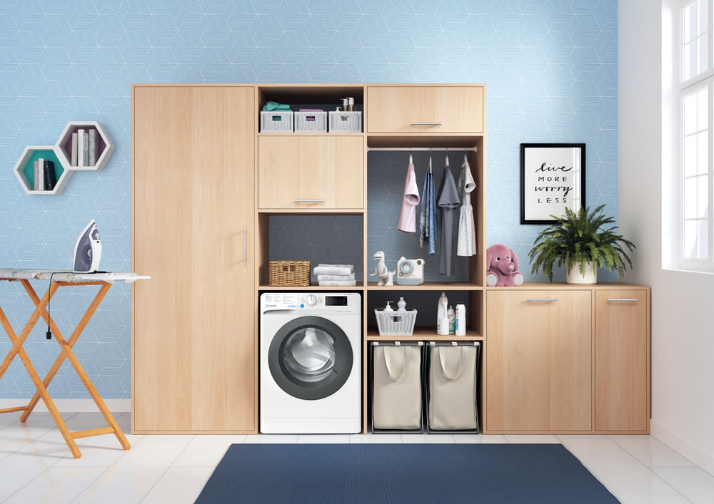 Moderna lavanderia con mobili in legno, una lavatrice, un asse da stiro e carta da parati blu.