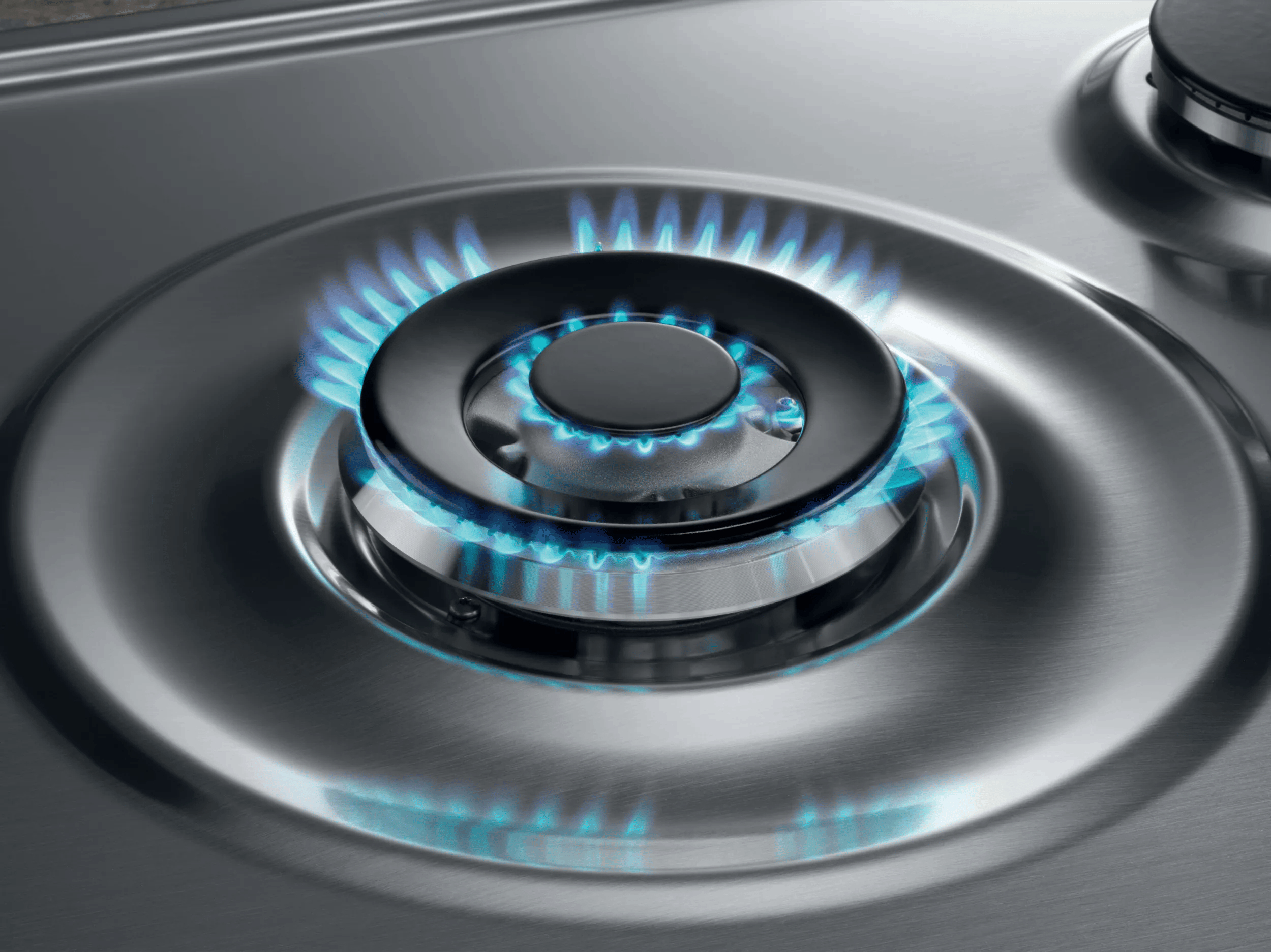 Una estufa de gas de acero inoxidable con un quemador encendido con llamas de color azul brillante.
