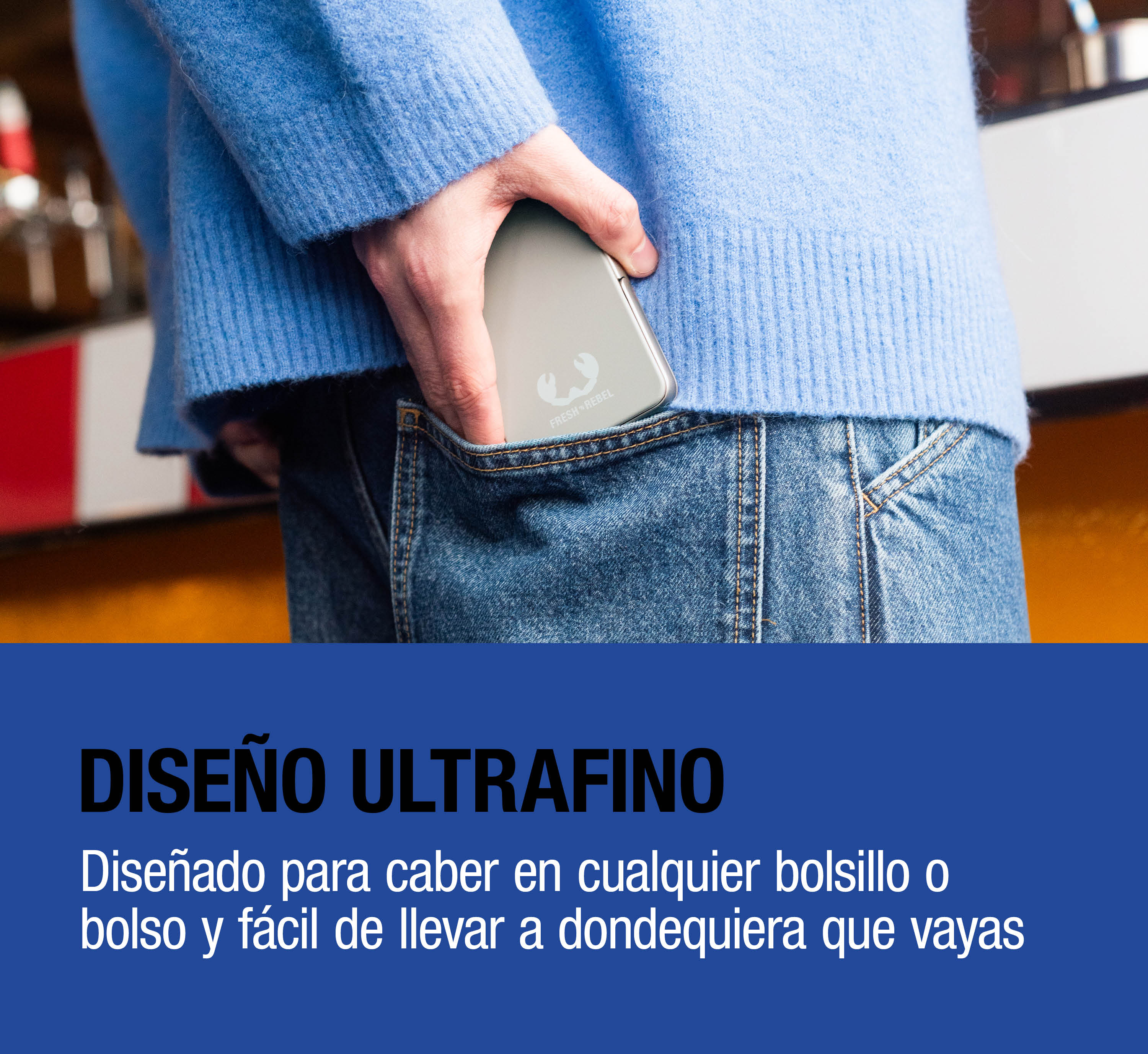 Una persona con maglione blu e jeans ripone un power bank argentato nella tasca posteriore.