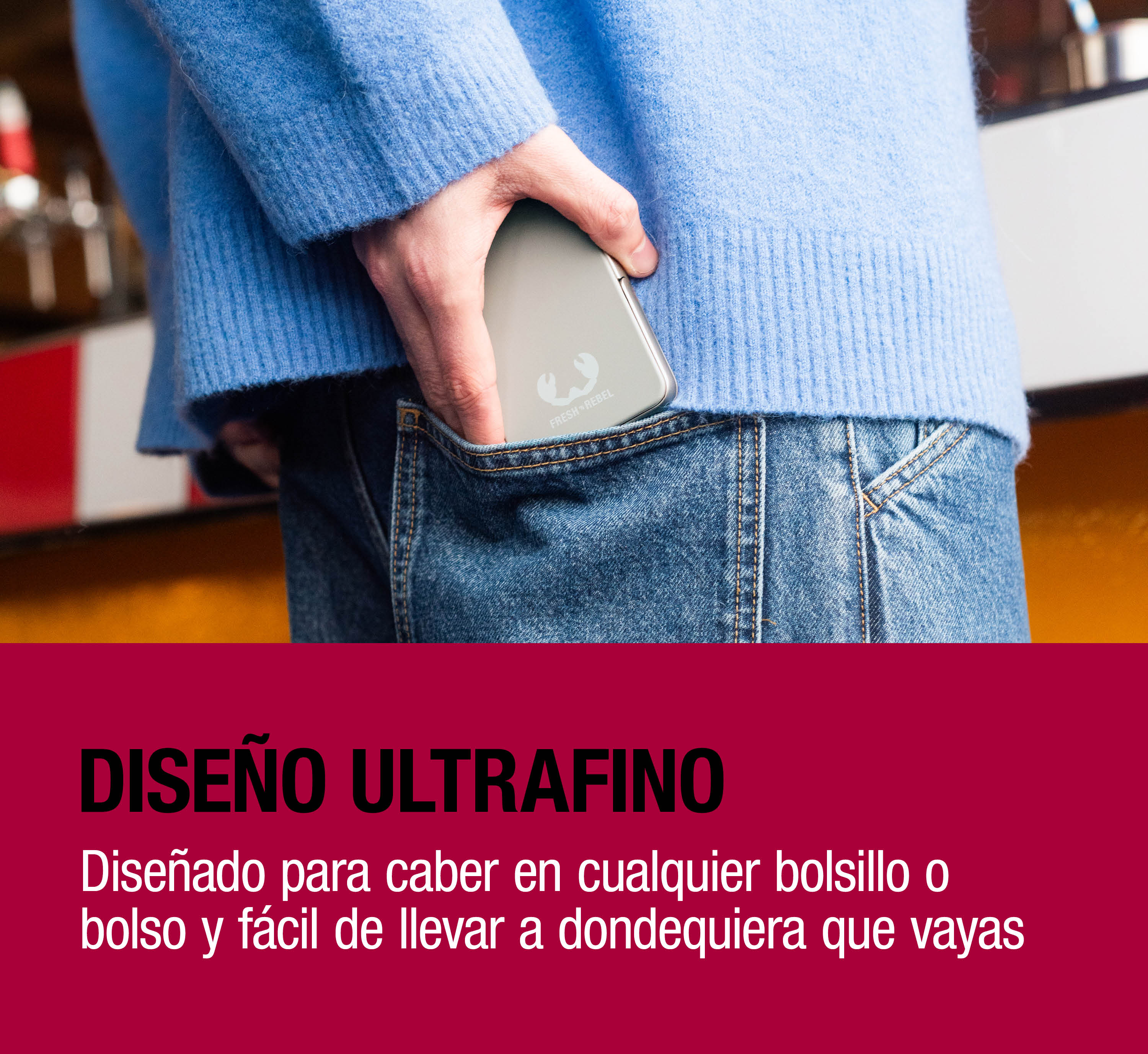 Una persona con maglione blu e jeans ripone una power bank argentata nella tasca posteriore.