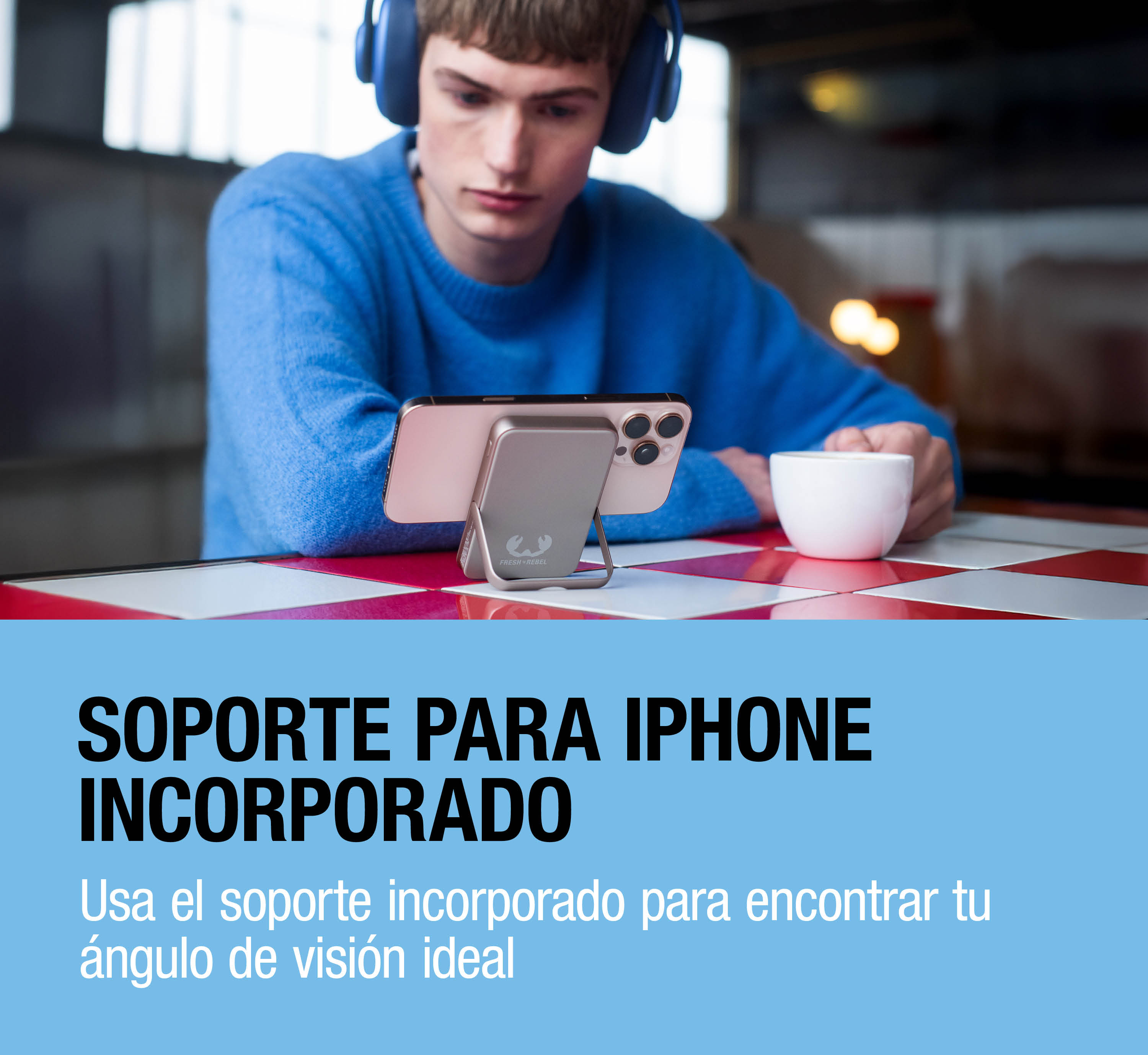 Un uomo con un maglione blu e le cuffie guarda un telefono su un supporto.