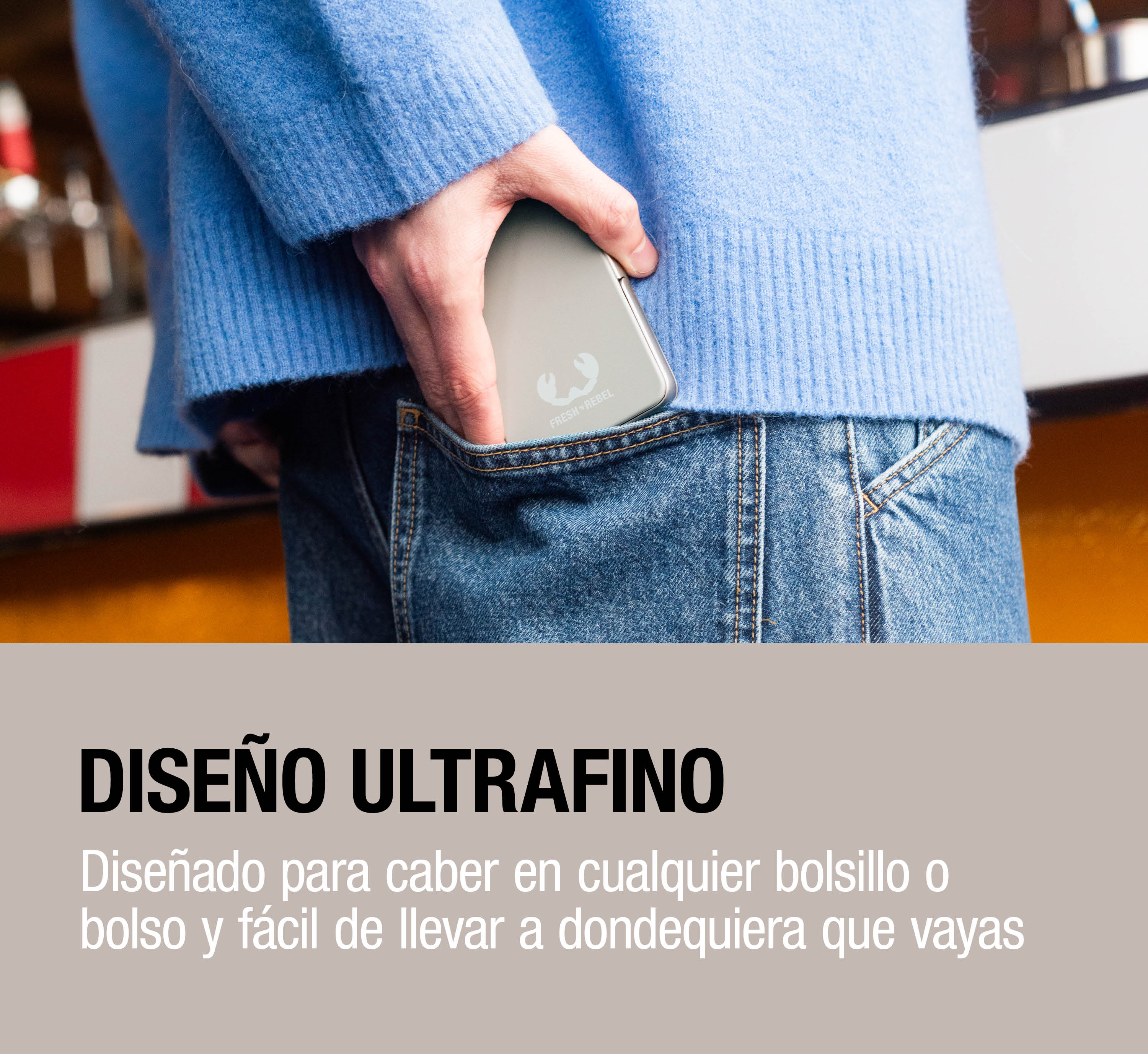 Una persona con un maglione blu mette un power bank nella tasca dei jeans.