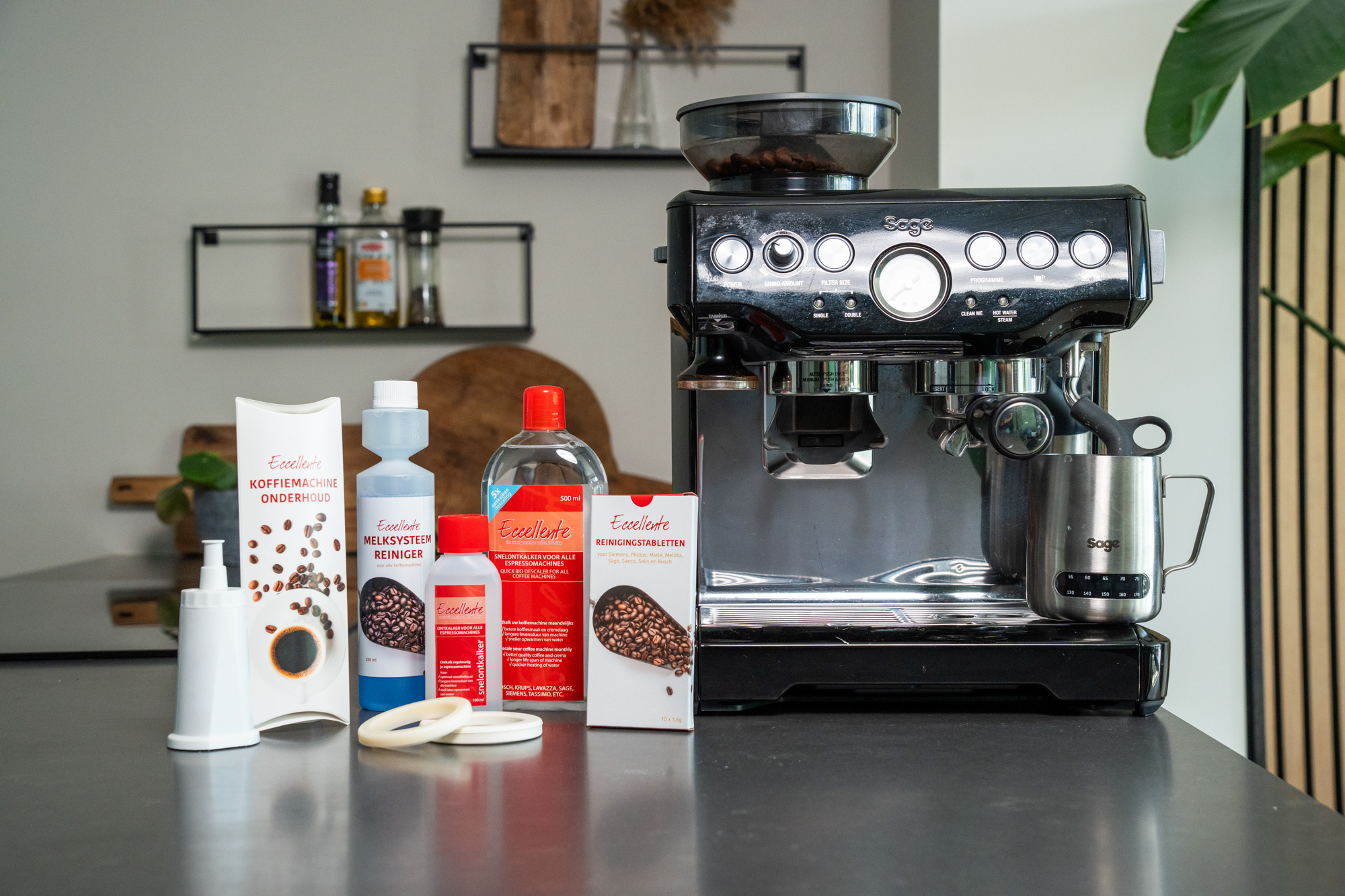 Black espresso machine with various cleaning products and maintenance items arranged on a kitchen counter.