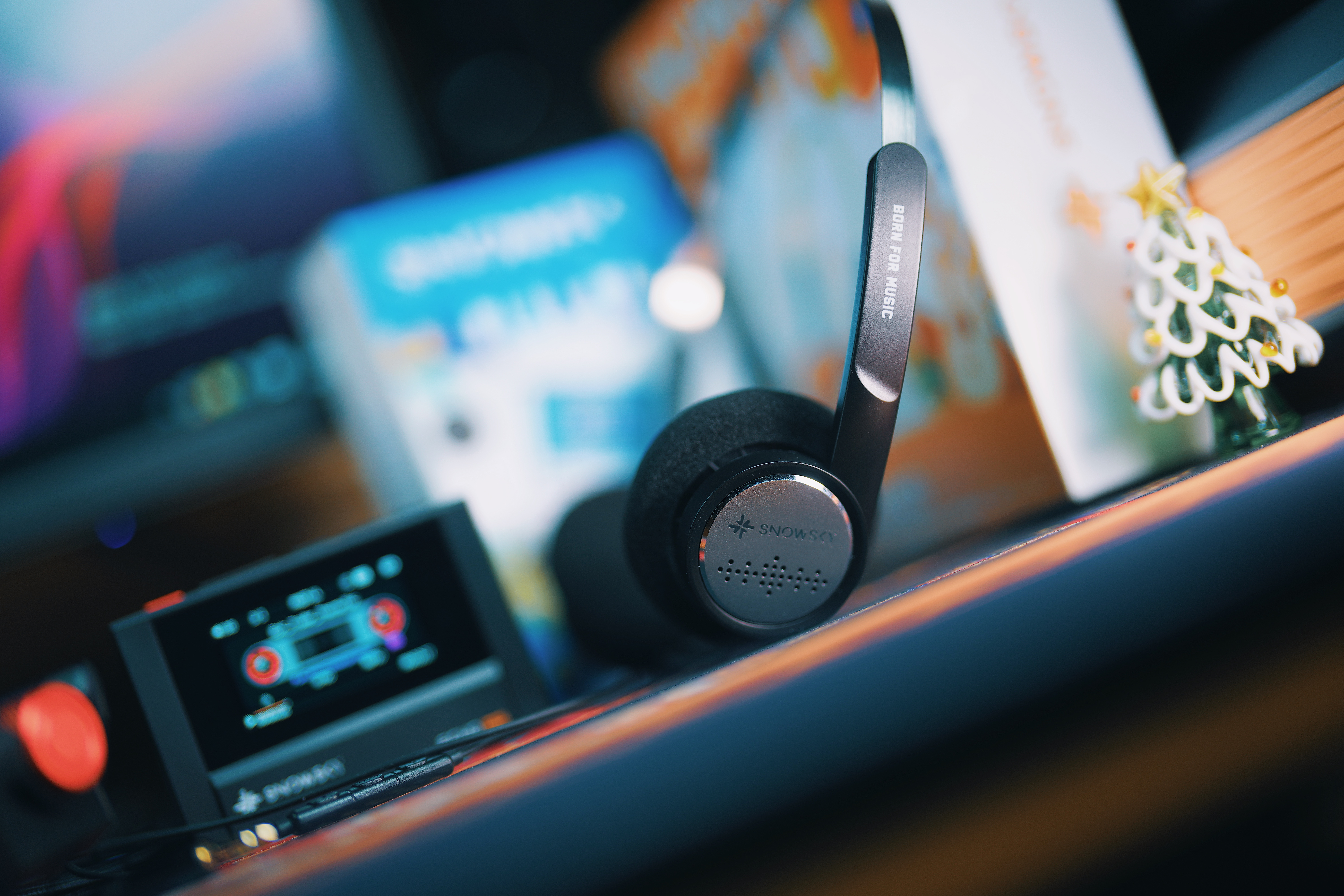 Los auriculares Snowsky descansan en un escritorio con reproductor y fondo difuminado.