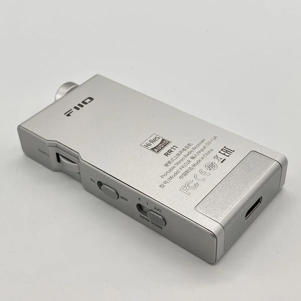 Un receptor de radio estéreo portátil FiiO RR11 plateado sobre una superficie blanca.