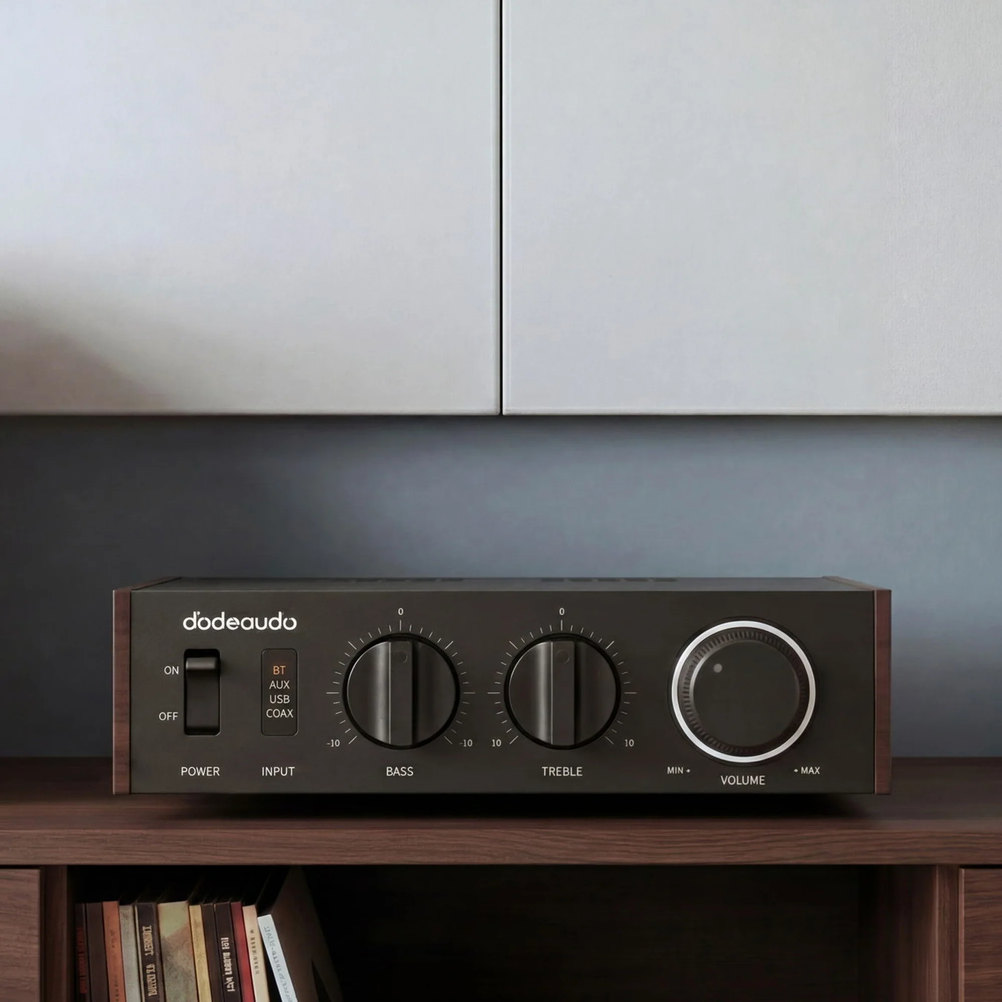 Un amplificador de audio negro con controles de graves, agudos y volumen sobre un estante de madera.