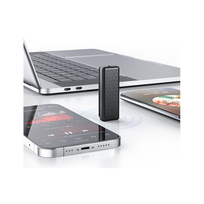 Un receptor de audio negro texturizado se encuentra junto a dos teléfonos inteligentes y una laptop plateada.