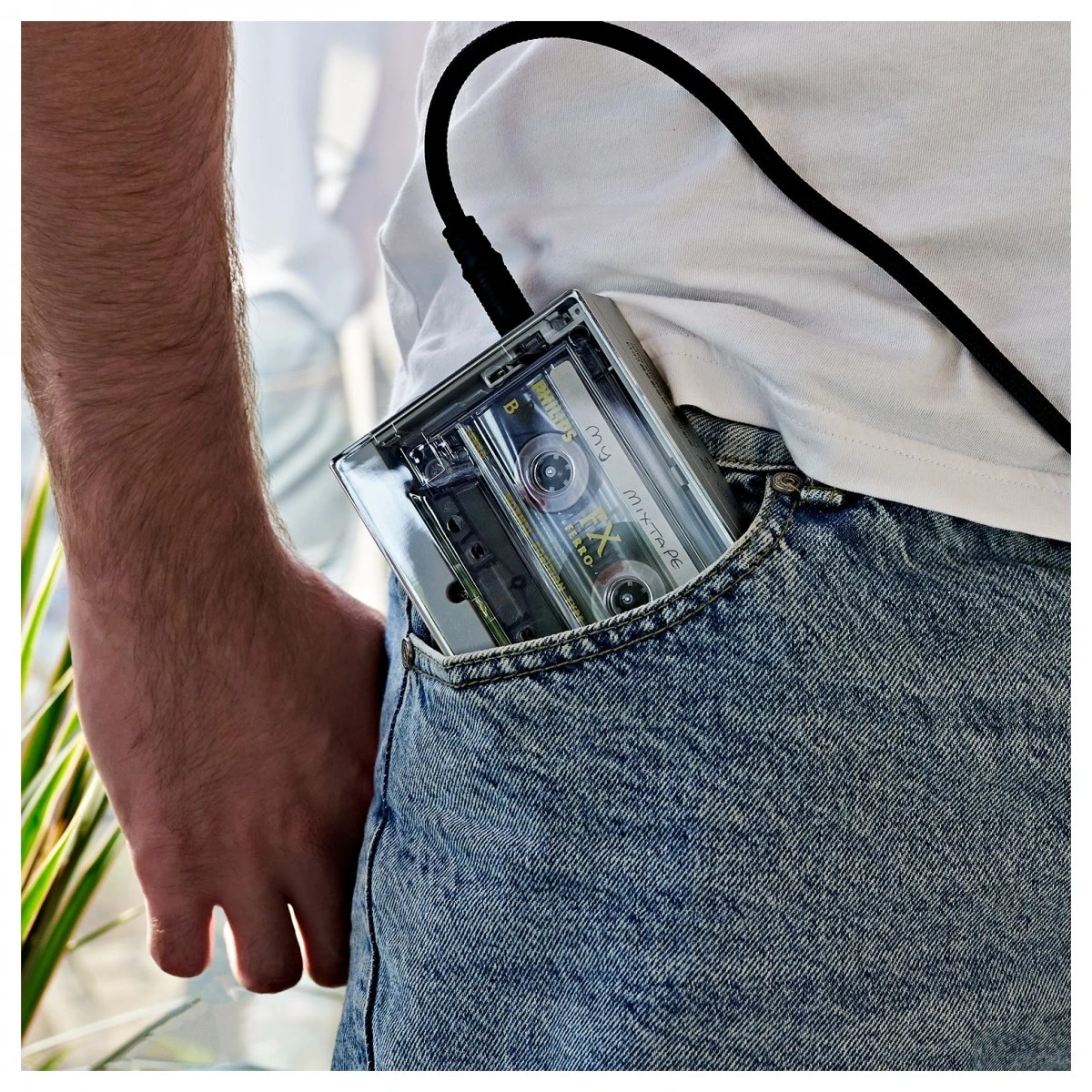 Een cassetteplayer met hoofdtelefoonkabel in de achterzak van een jeans.