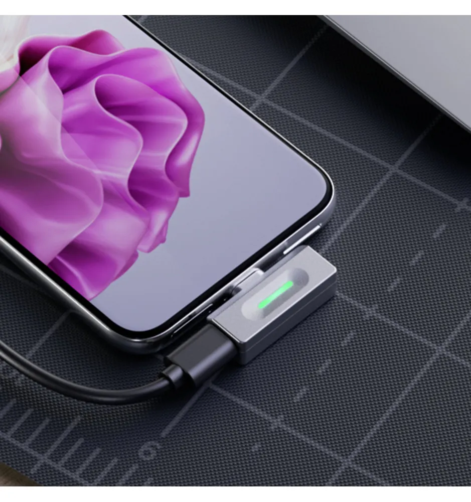 Szary adapter jest podłączony do smartfona z różowym kwiatowym tłem i świeci na zielono.