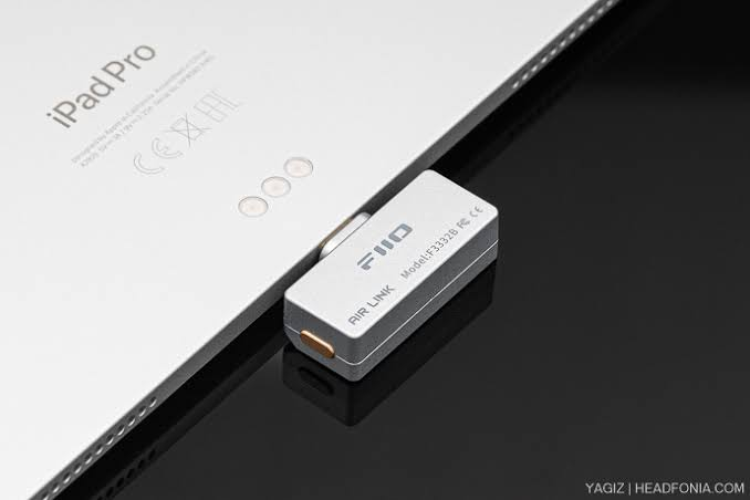 Srebrnoszary adapter FiiO Air Link jest podłączony do tyłu srebrnego iPada Pro.