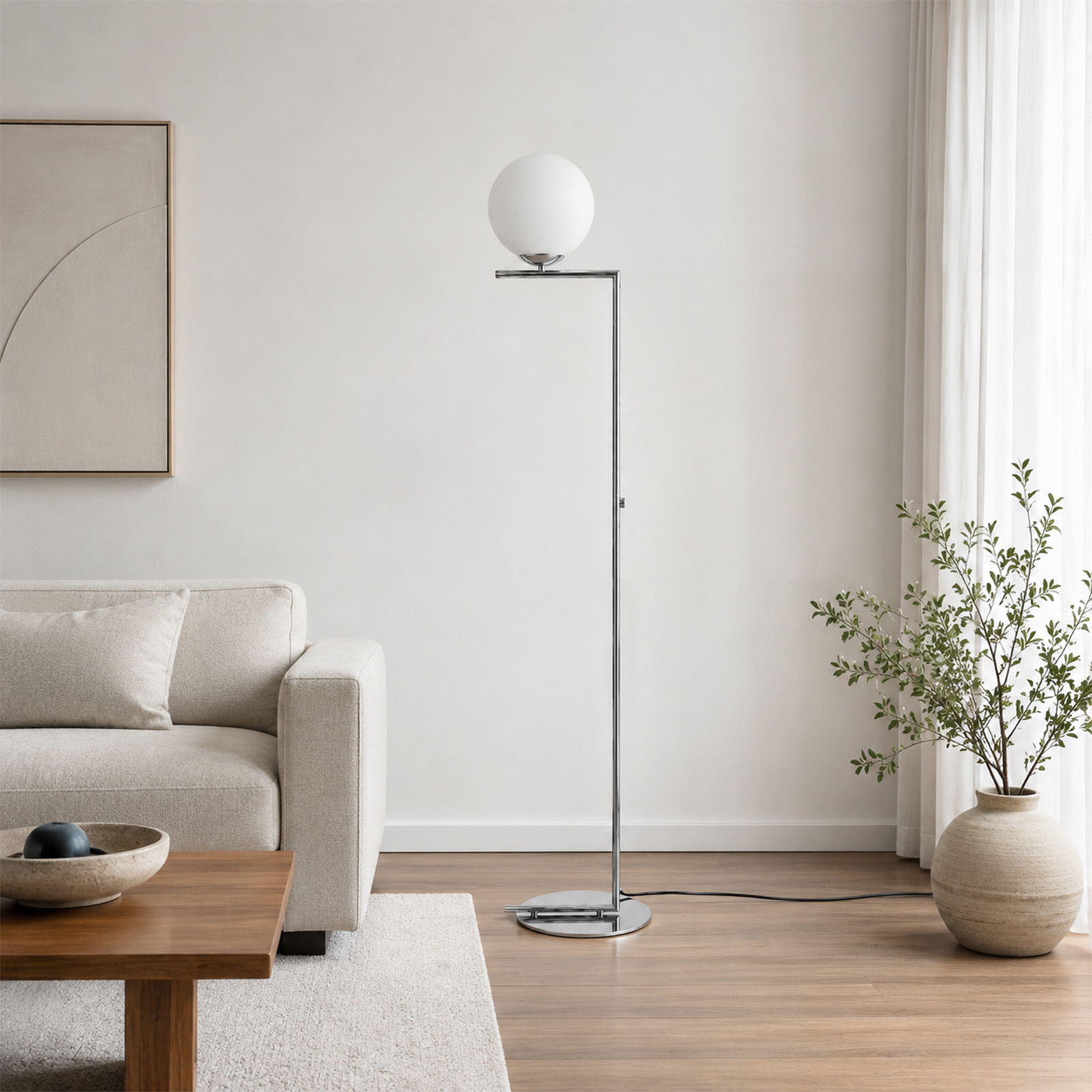 Una sala de estar moderna cuenta con un sofá beige, una lámpara de pie cromada con pantalla esférica y una planta.