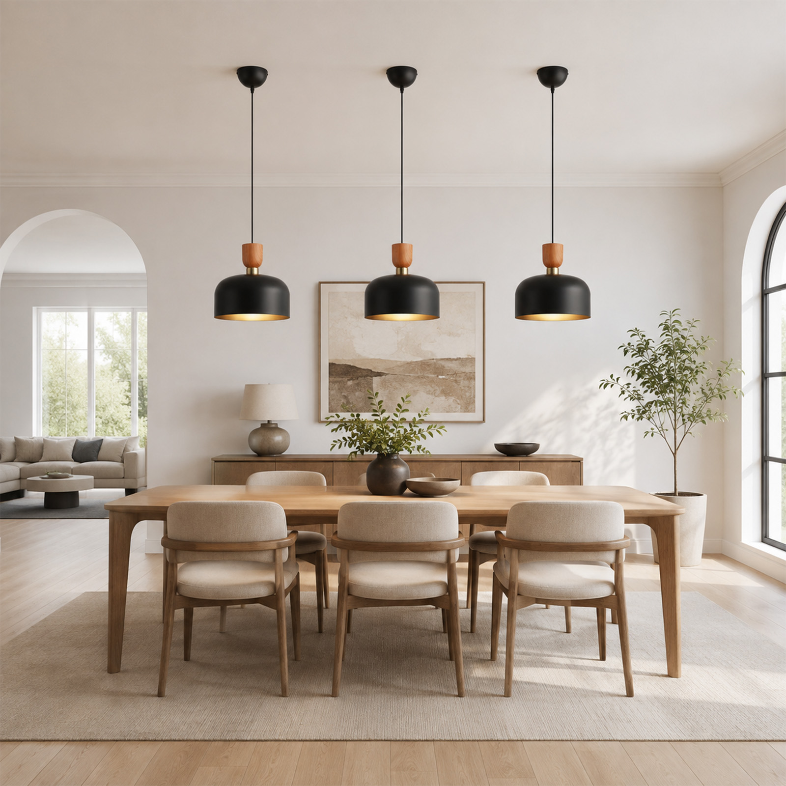 Un comedor luminoso con mesa de madera, sillas crema, tres lámparas colgantes negras y plantas.