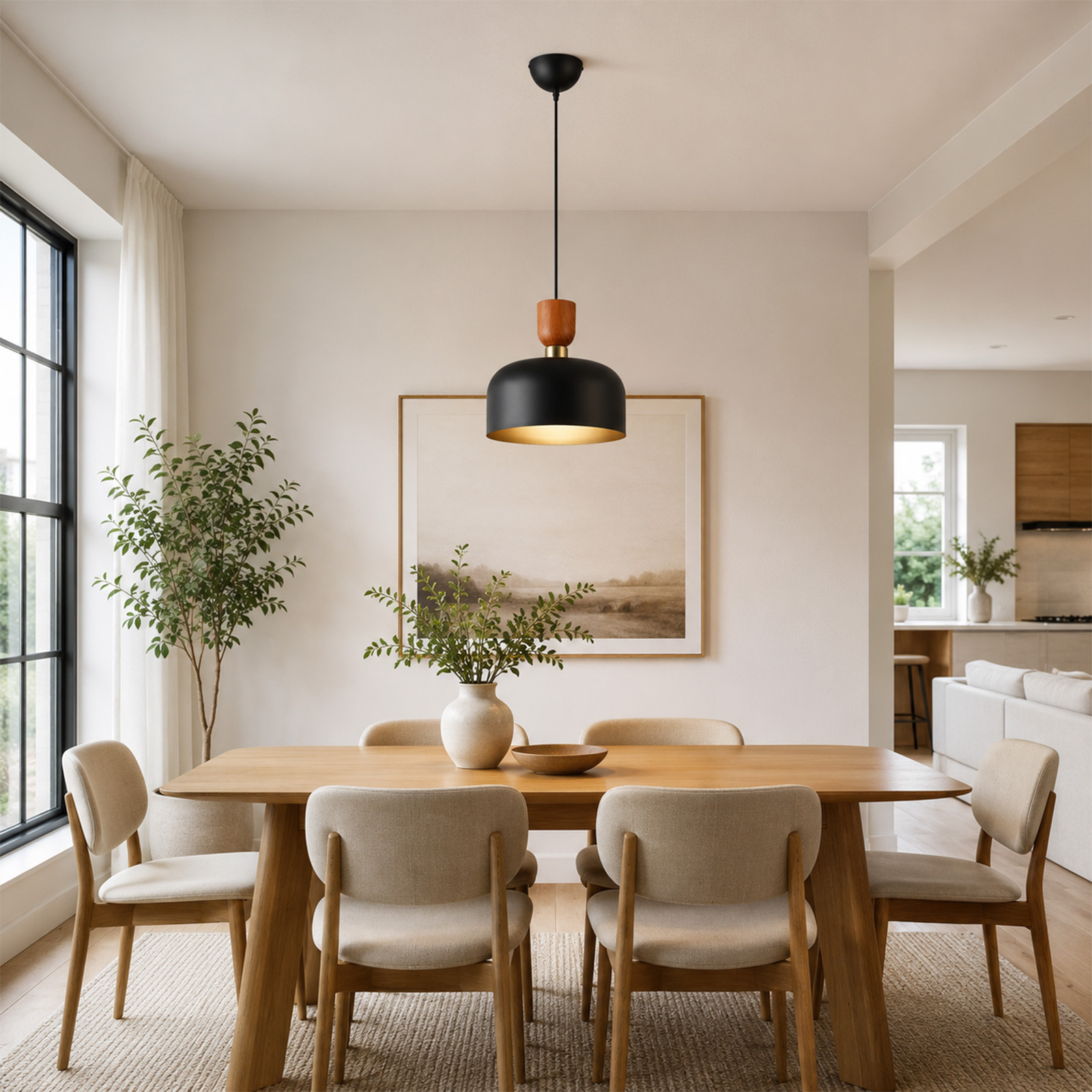 Una mesa de comedor de madera con sillas beis, un florero con vegetación y una lámpara colgante negra en una sala moderna.