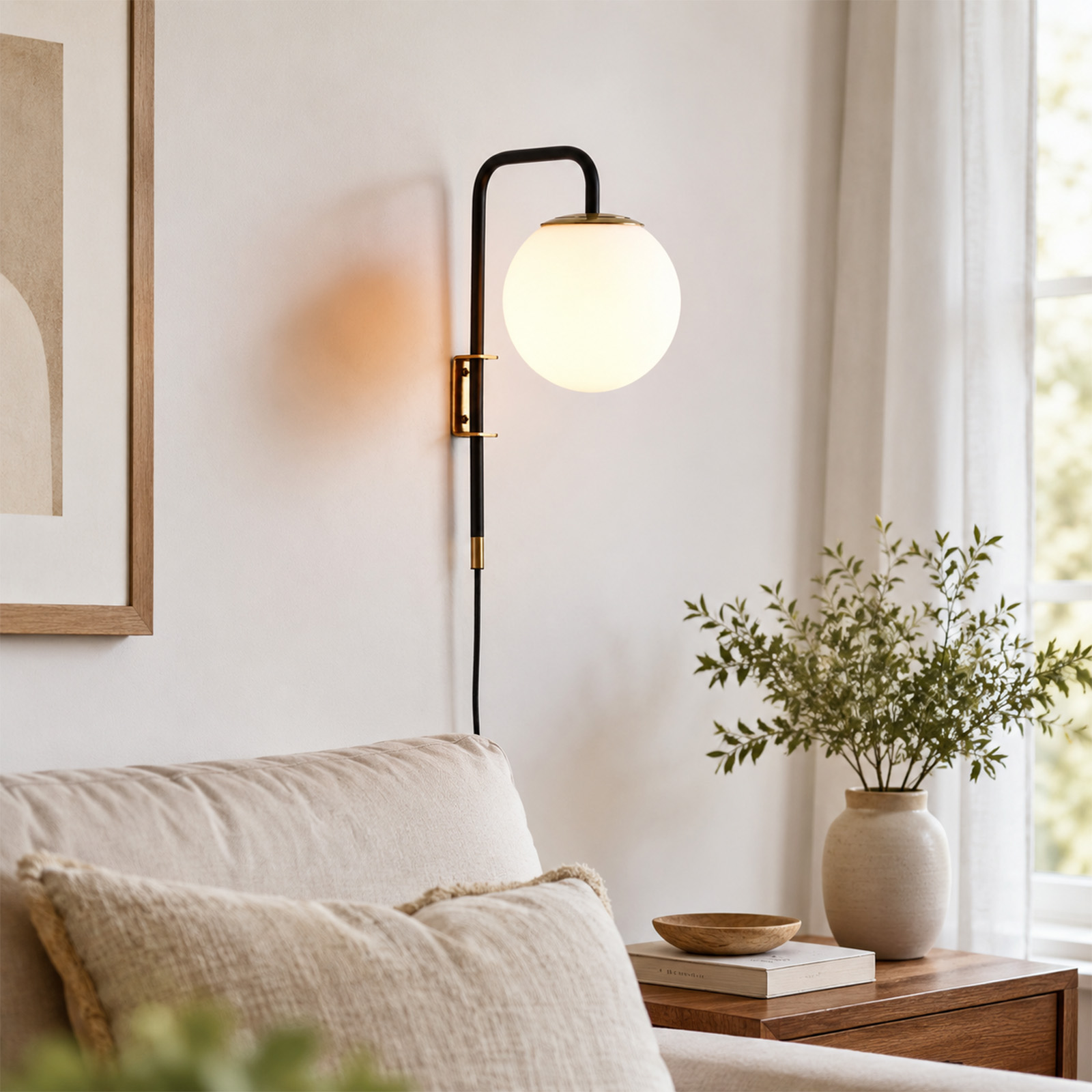 Un aplique de pared negro y dorado con globo de cristal ilumina sobre un sofá beige y una mesa de madera con jarrón.