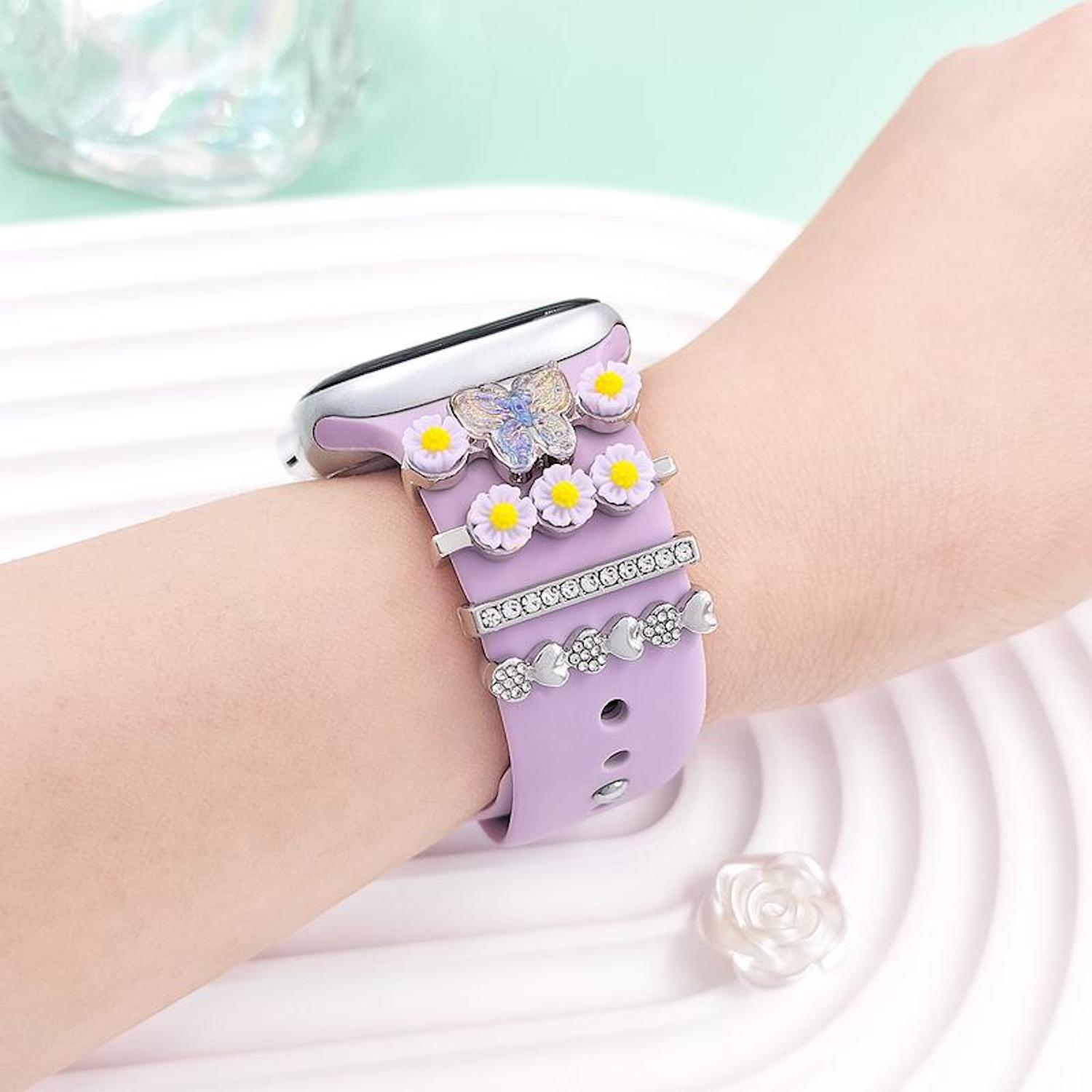 Lila Smartwatch-Armband mit Blumen-, Schmetterlings- und Glitzer-Charms am Handgelenk.
