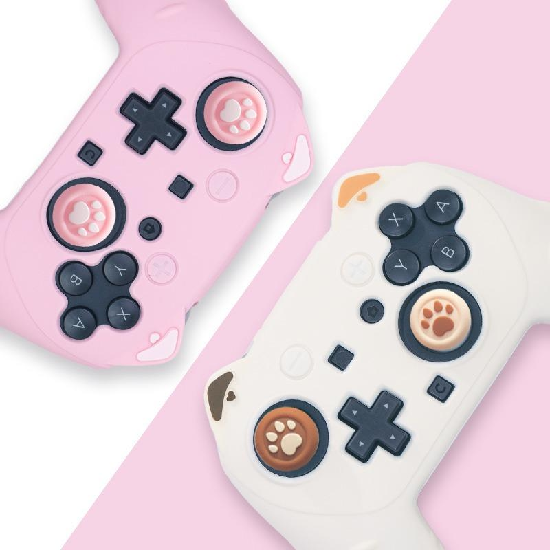 Zwei süße Gaming-Controller in Rosa und Weiß mit Pfoten-Design auf den Analogsticks vor einem rosa Hintergrund.