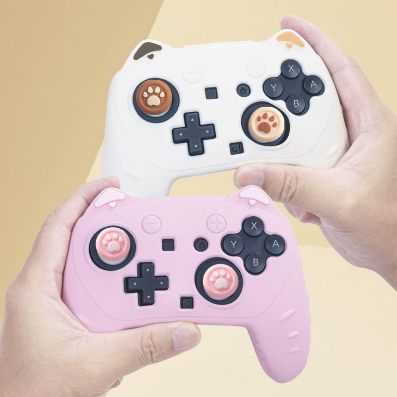 Zwei Hände halten weiße und rosa Gamepads im Katzen-Design mit Tatzen-Joystick-Kappen.
