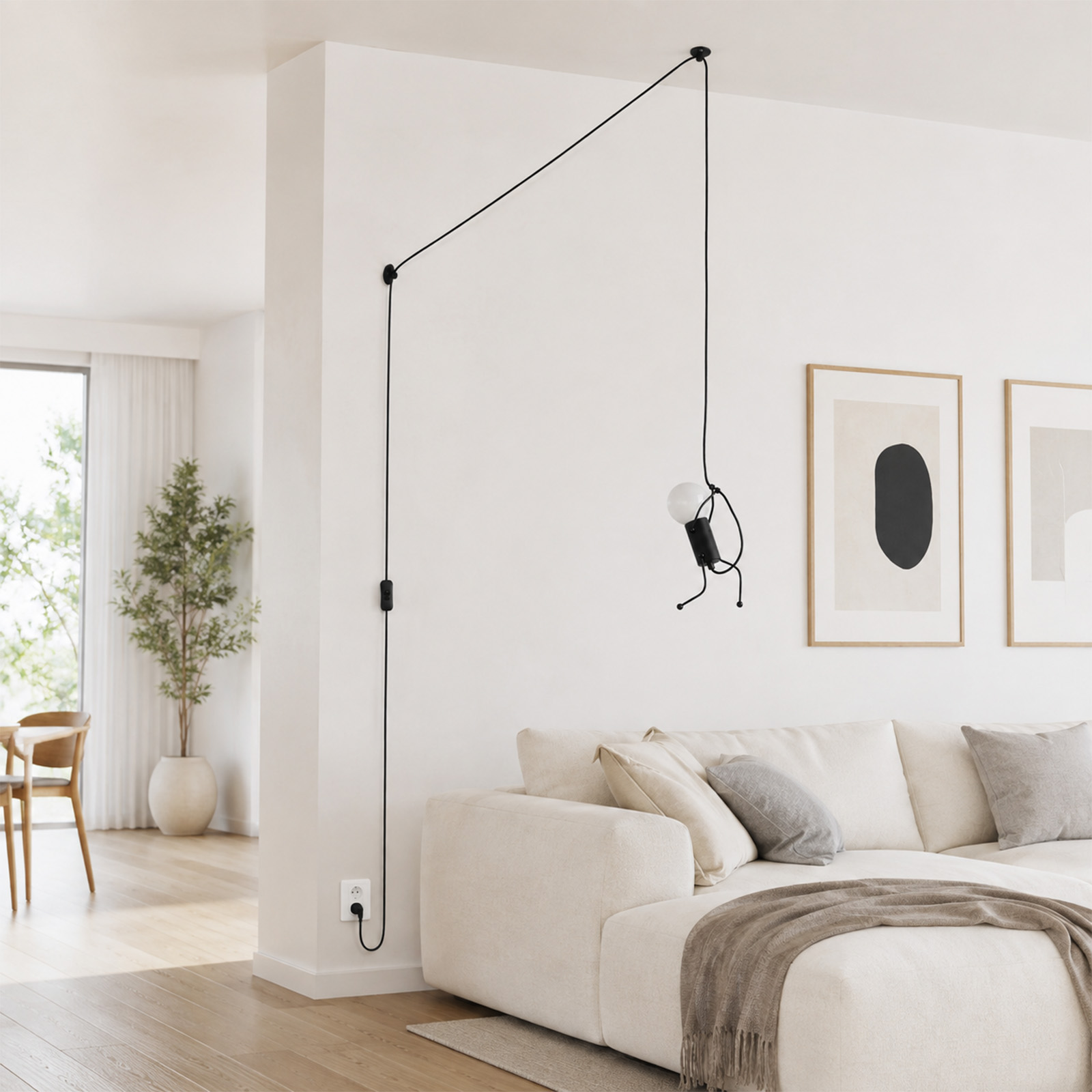 Una sala de estar moderna con un sofá claro, una lámpara negra colgante en la pared blanca y obras de arte.