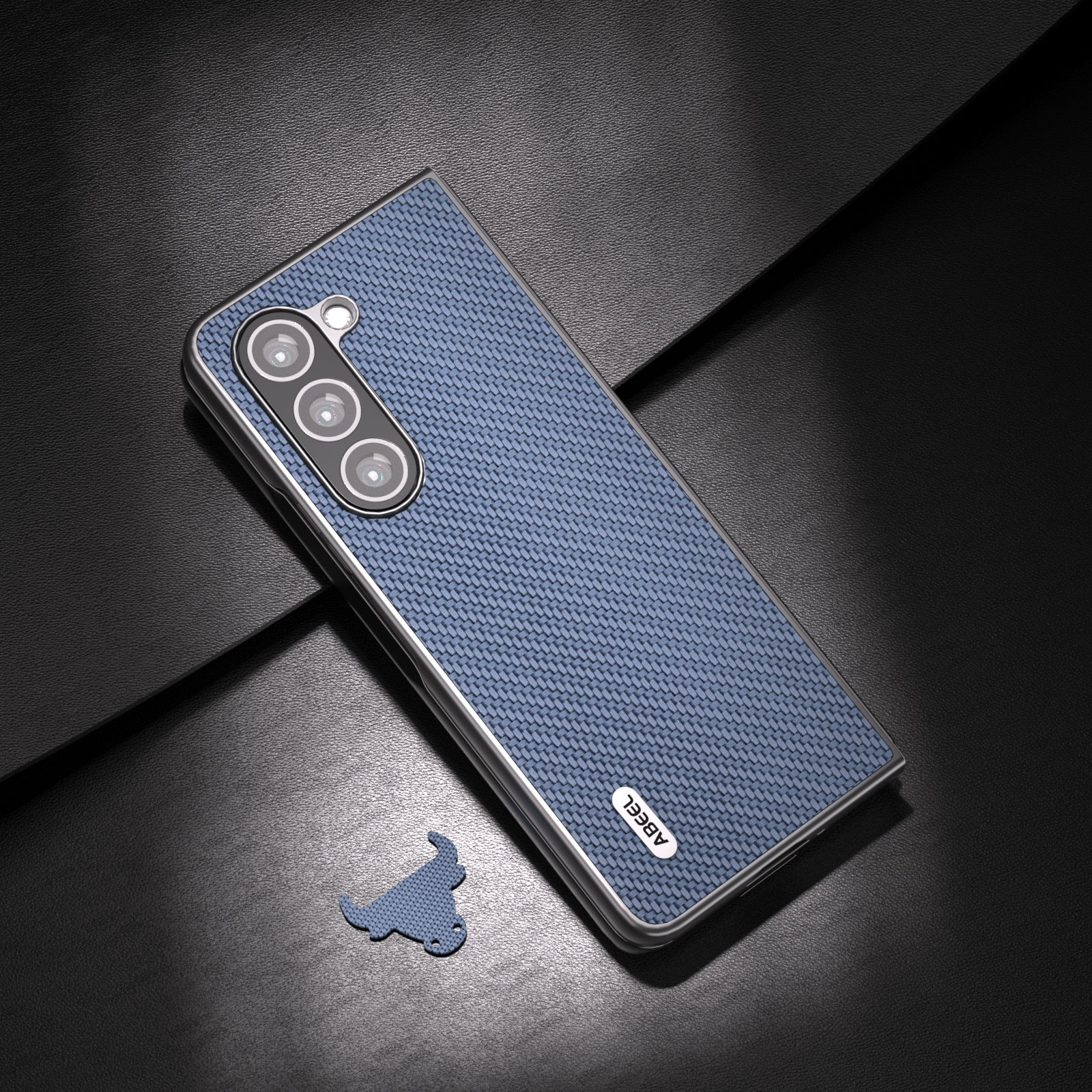 Eine blaue Smartphone-Hülle in Flechtoptik mit drei Kameralinsen liegt neben einem kleinen Stier-Logo auf dunklem Grund.