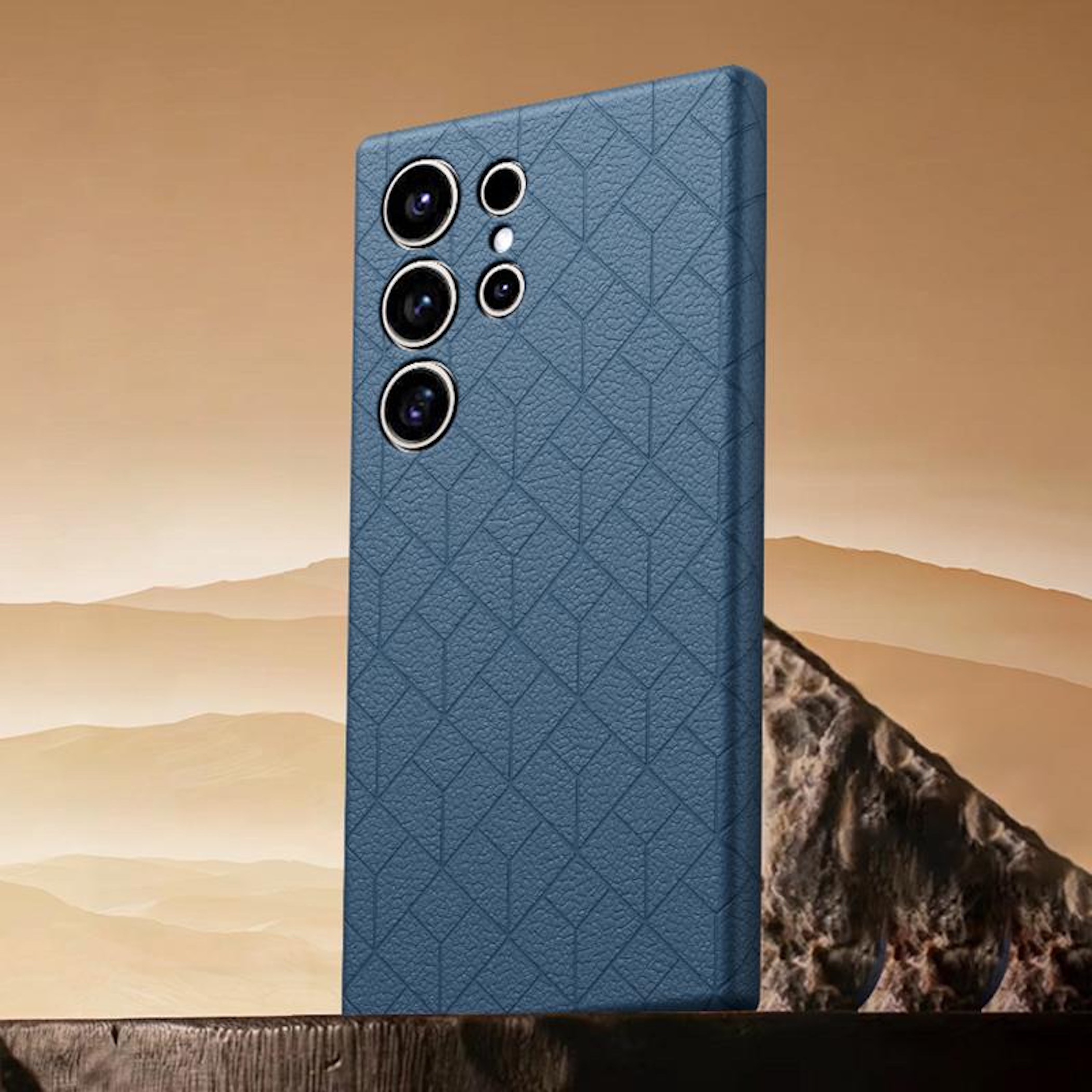 Eine blaue, texturierte Smartphone-Hülle steht aufrecht auf einer Oberfläche vor einer Wüstenlandschaft.